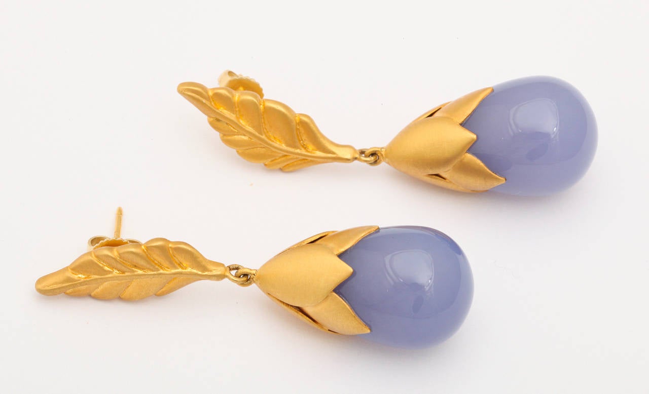 A pair of earrings composed of chalcedony drops with 18kt yellow gold feather caps. The caps are suspended from 18kt yellow gold leaf studs.
Length: 2:00 inches
width: .60 inch