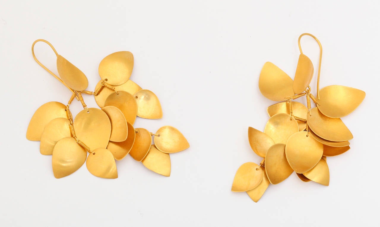 A pair of 18kt yellow gold leaf earrings. The leaves have been wire wrapped and are attached to a handmade wire chain. The cluster of leaves is suspended from an 18kt yellow gold leaf and ear wire.