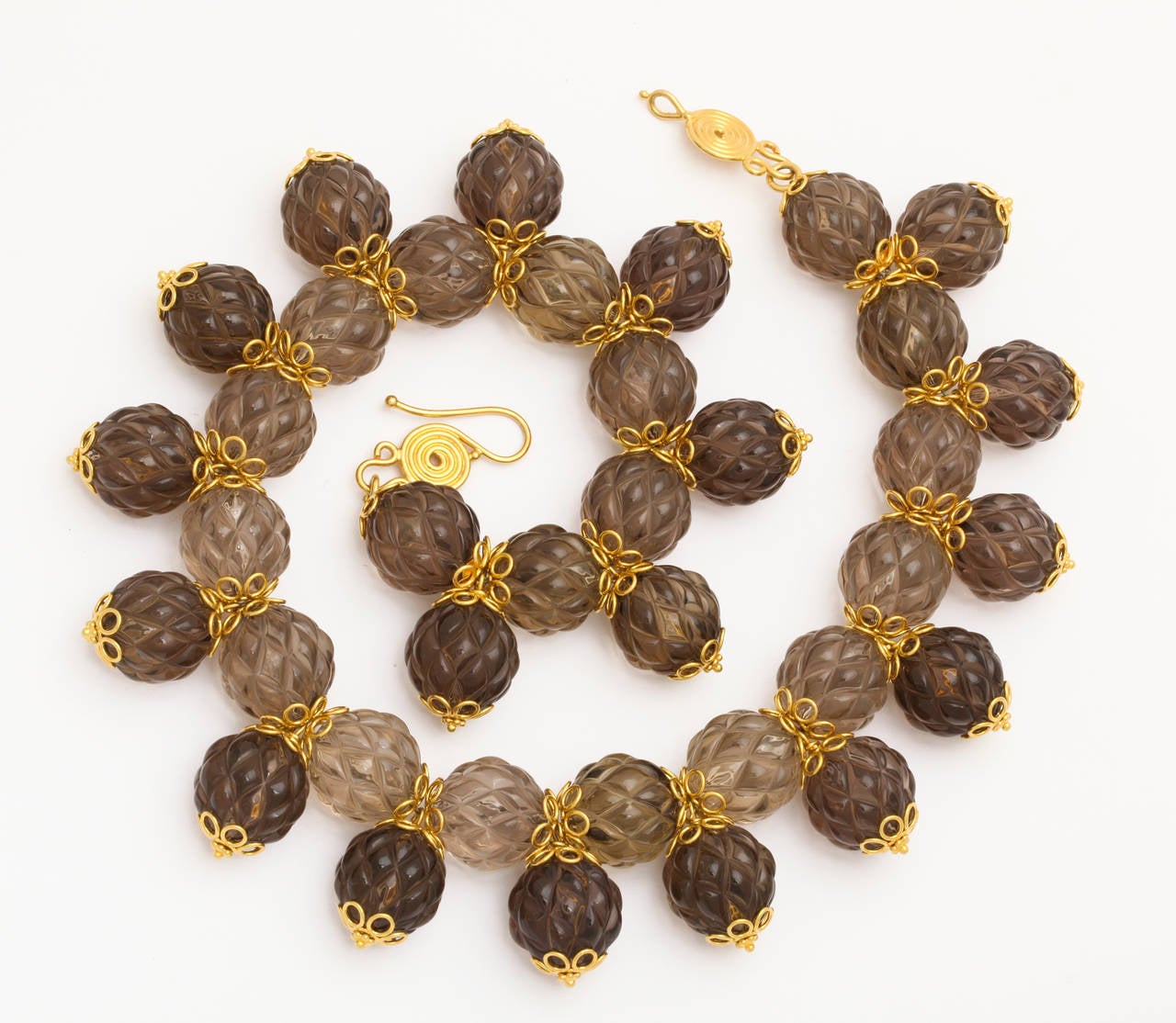 A necklace composed of carved smokey quartz beads, 18kt yellow gold flower caps, 18kt yellow gold headpins and an 18kt yellow gold clasp.
Length:18 inches
width: 1.50 inches