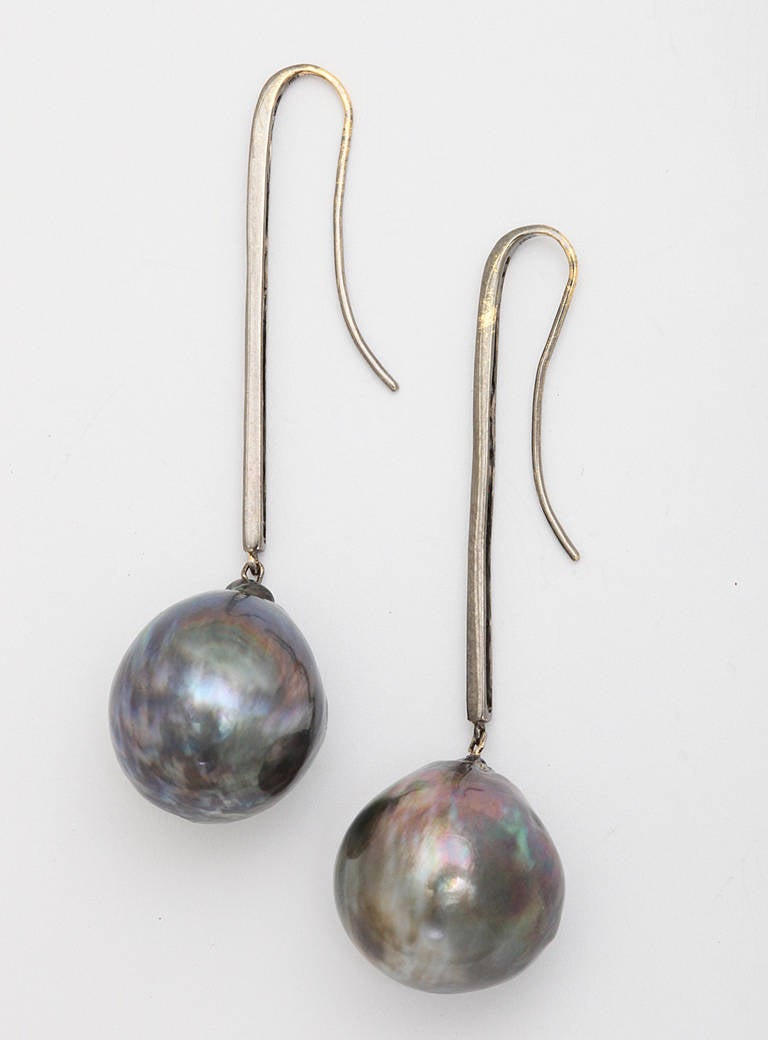 A pair of south sea pearl and diamond earrings. The pearls are suspended from rhodium plated 18kt gold sticks that are set with diamonds. The pearls measure 17.5mm and 18mm.