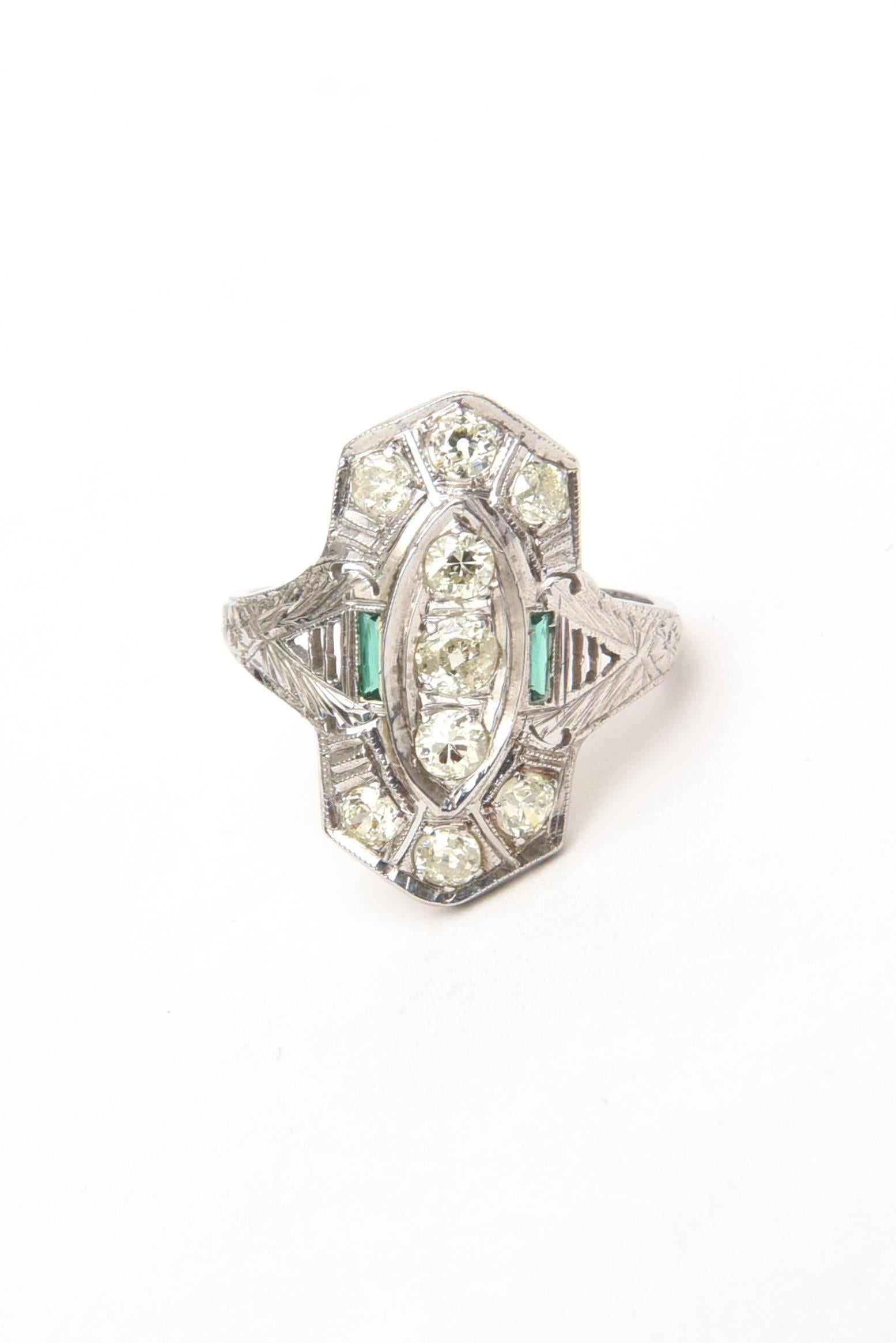 This lovely art deco period 18 karat white gold ring has 9 round old mine cut diamonds of .45 carat total weight in diamonds.
The two green green stones are glass and look to resemble emeralds.
it is stamped 18K.
Is is 2.6 DWT or penny weight.
The