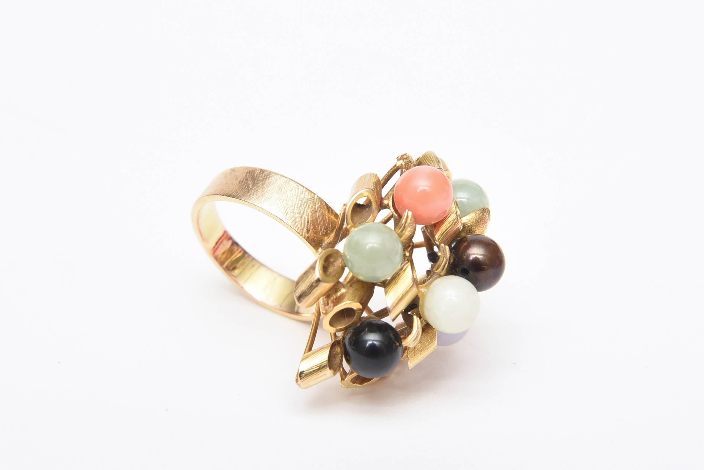This 1960's vintage cluster sculptural cocktail dome ring has beautiful detail of the 14K yellow gold in spiral forms interspersed with various round stones of jade, coral, amethyst and black and white onyx. It is lovely on the finger as it has a