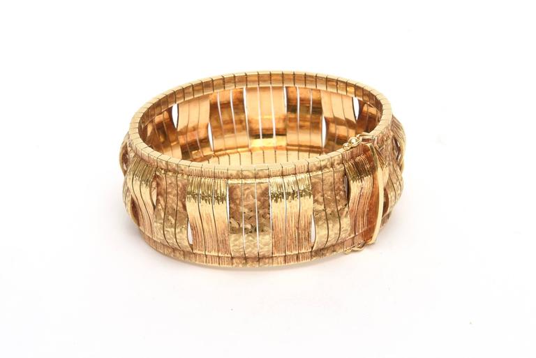 This thick and stunning vintage Italian sculptural bracelet is stamped 18K Gold. It has great weight and presence. it has 3 rows of 18 K yellow gold that is recessed and 3 rows that is frontal giving it it's sculptural entity. It has an in and out