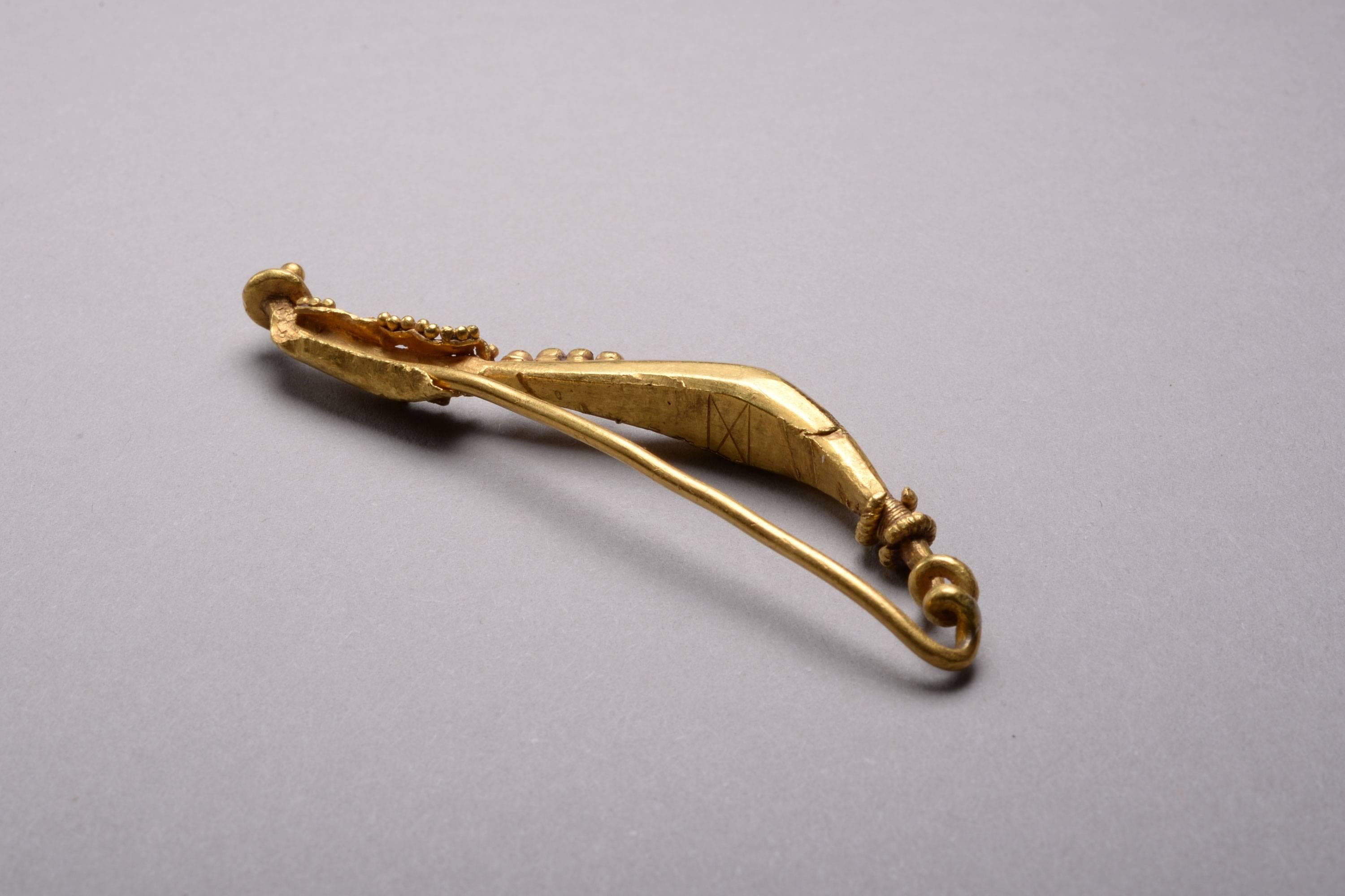 A stunning and elegant ancient Romano-Celtic solid gold brooch, dating to around 50 BC - 10 AD. The shape of this fibula is extremely rare, and this is an honest, genuine example in a market plagued by forgeries.

This striking brooch has a