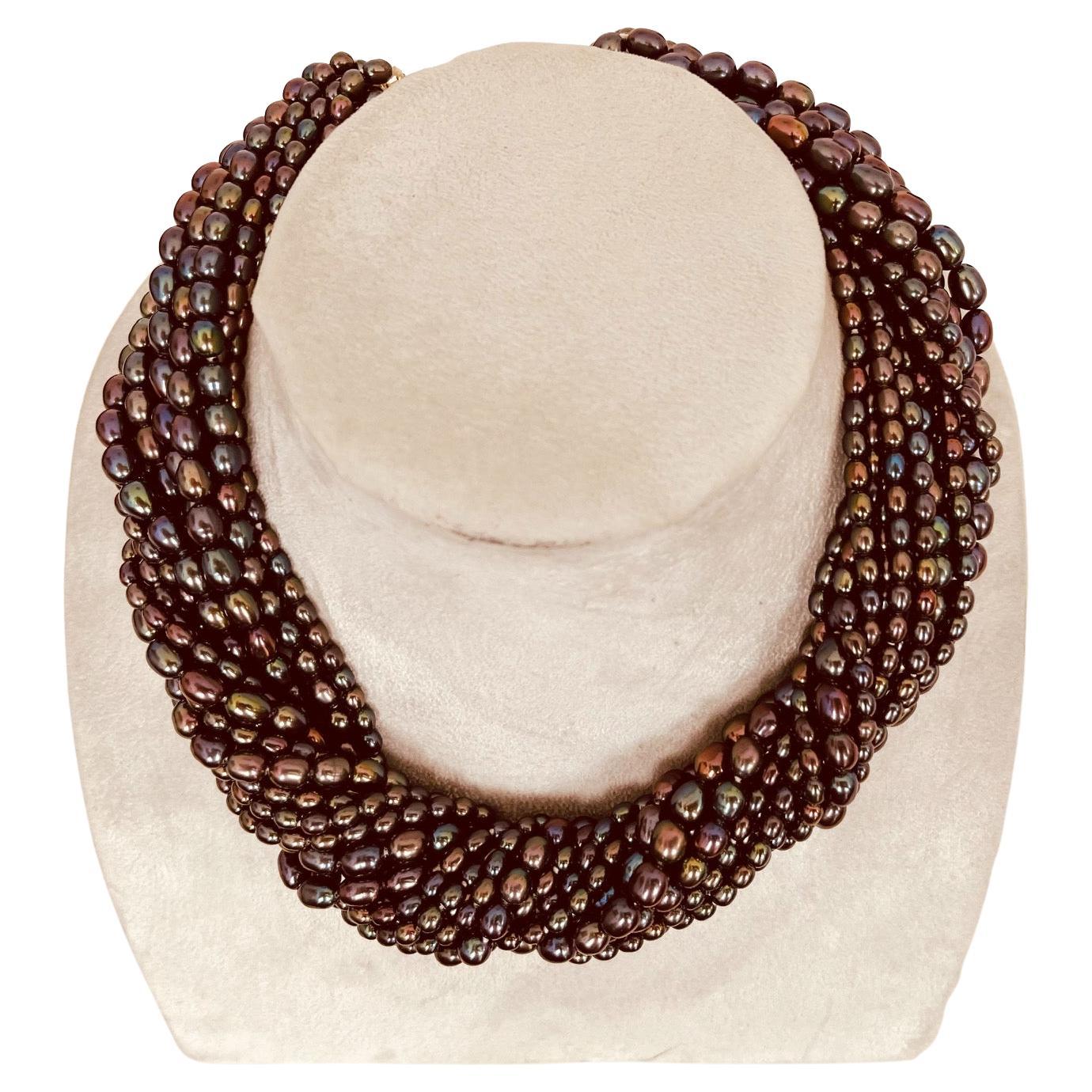A multi row dyed black cultured pearl necklace of varying oval sizes beads connected to a pair of 18ct gold fasteners. Circa 1990. Maximum length 41cm. 17 rows beads varying from 3mm to 5mm. Diameter of rows 17mm. Pearls' origin is China and clasp's