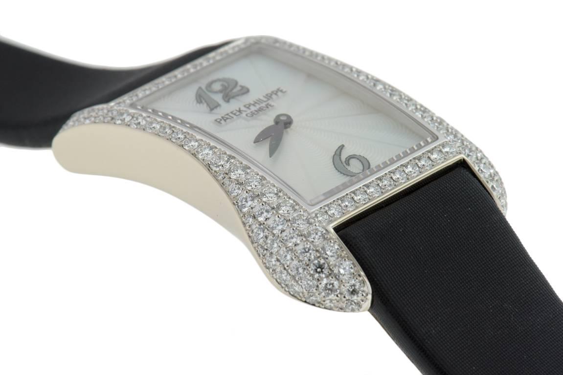 Ladies Patek Philippe Gondolo in 18K white gold, Ref#4972G-001. On original satin strap with 18K white gold tang buckle, case set with 130 diamonds, case dimensions  27.4 x 39.7 mm. Quartz movement. White mother of pearl guilloche dial with Arabic