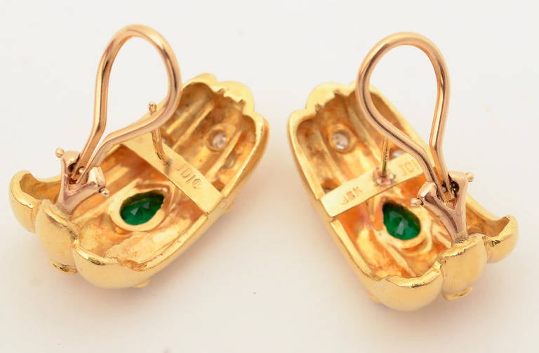Substantial size 18 karat gold earrings with three ribs centered with a pearl shaped emerald and surrounded by 6 round diamonds. Omega backs. Maker's mark JDI.