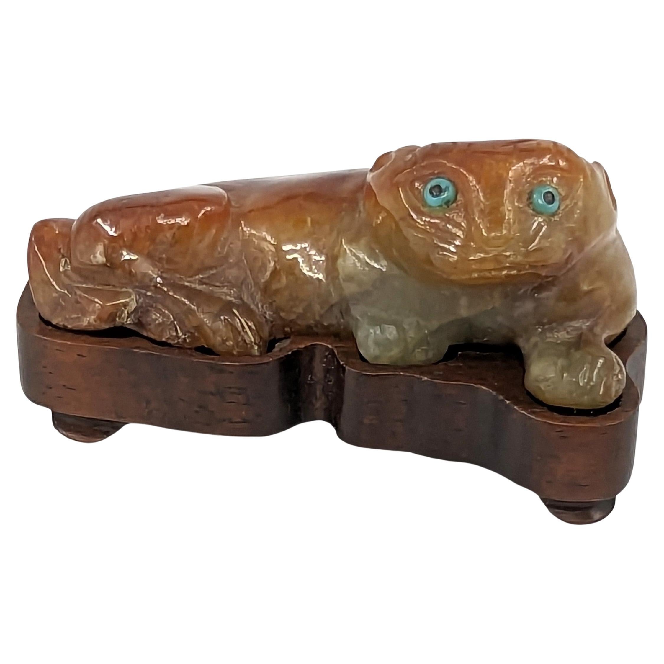 A wonderful and cute antique Chinese carved jadeite recumbent cat, comfortably nested in a matching hardwood stand. The almost fluffy looking cat's intense greenish blue eyes are inlaid with turquoise cabochons with black dot centres, and has a tail