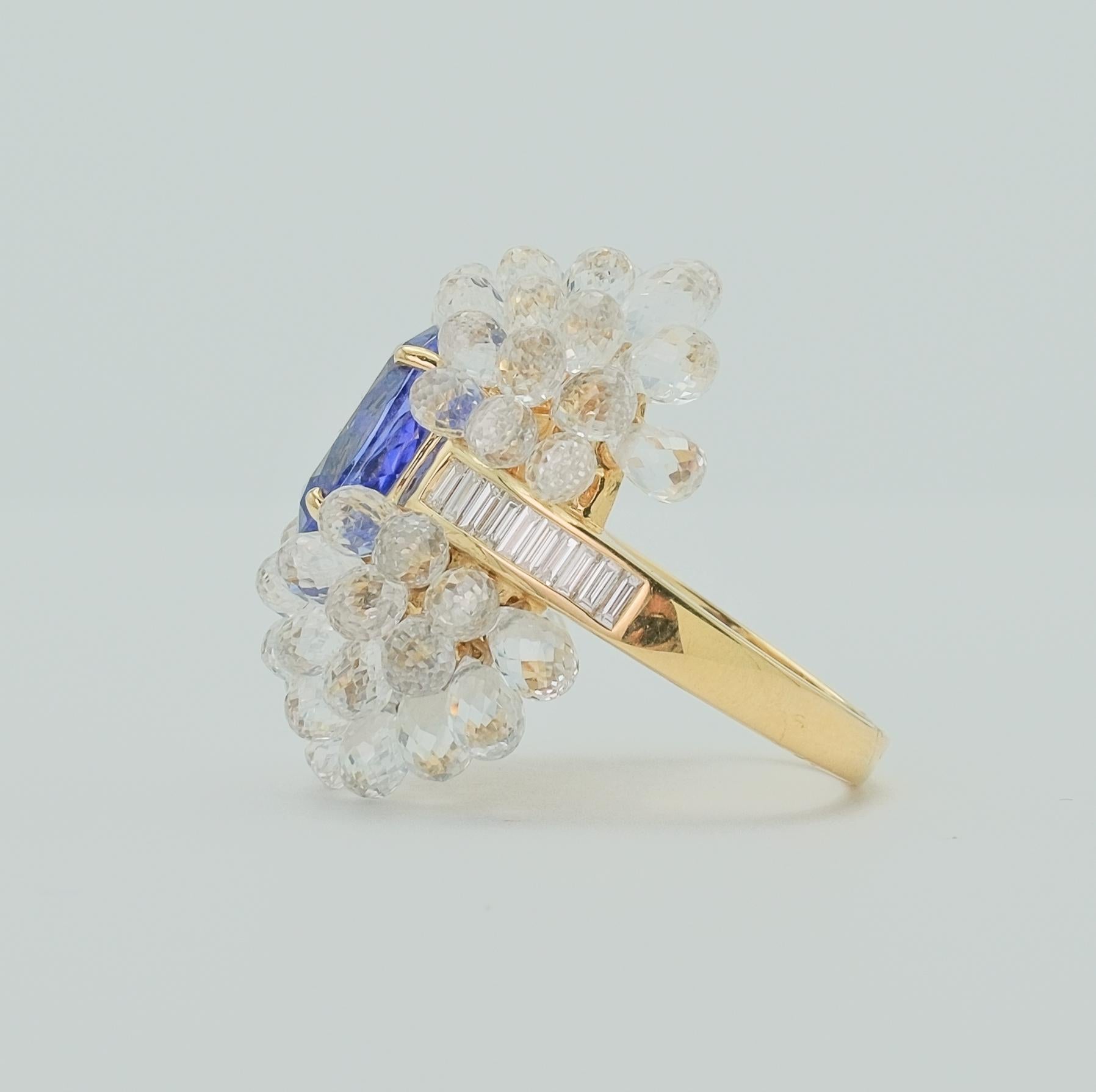 Incredibly well made ring with a tanzanite center stone surrounded by a bouquet of precisely cut white sapphires on a yellow gold band with baguette diamonds. The tanzanite is approximately 4.3 carat with 20 diamonds measuring .50 carats. The white