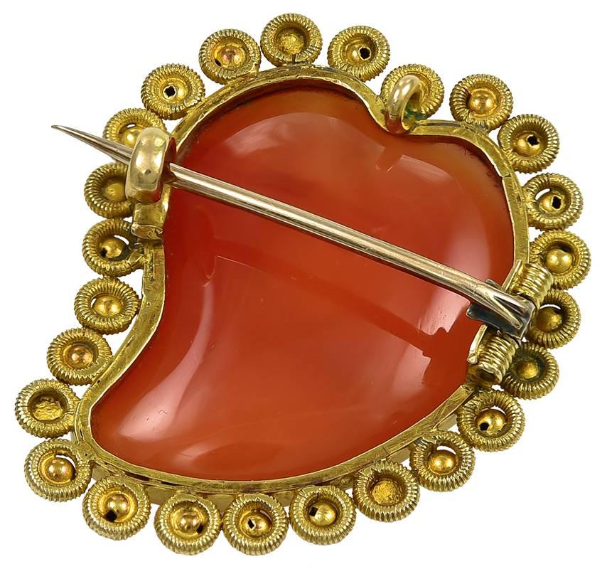 The Witches Heart carved from a good colour piece of Carnelian with a slightly domed top and reverse. The fine Canatille work Gold frame is in excellent condition as is also the pin and clasp on the reverse and there is a small original loop at the