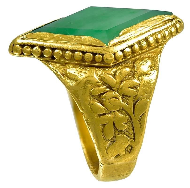 The Jade Marquise shaped stone of a luminous deep apple colour which is set in a richly coloured Gold mount with bead work rim and with floral embossed shoulders. There are clear and readable Chinese character marks stamped inside the shank and also