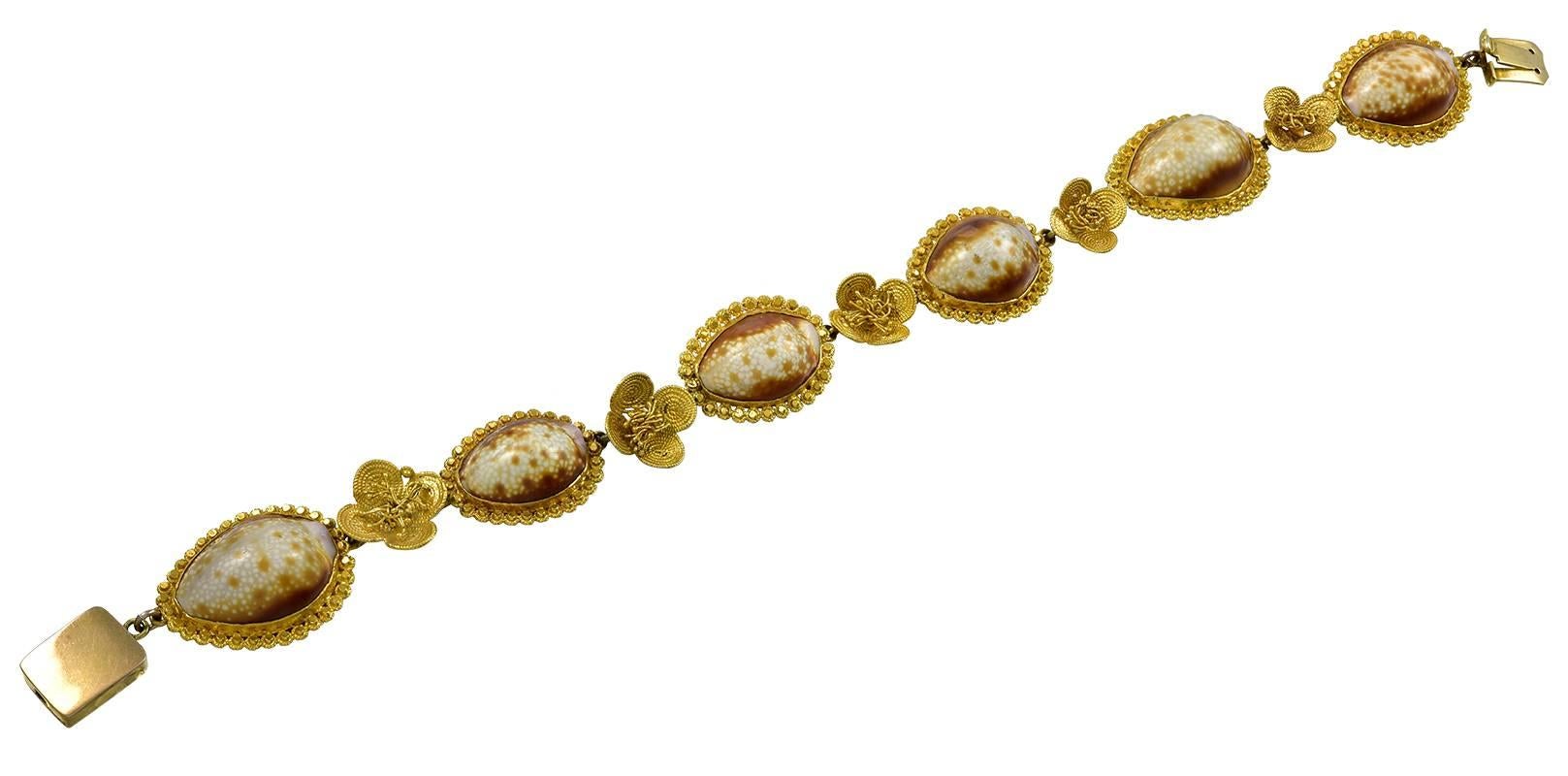 The 6 Cowrie Shells are set in hand made Gold Canatille Work frames, alternating with Gold Buttercup Flowers to a square box clasp.
In 18th century England, people were intrigued with the exotic Cowrie Shells, which were brought back by returning