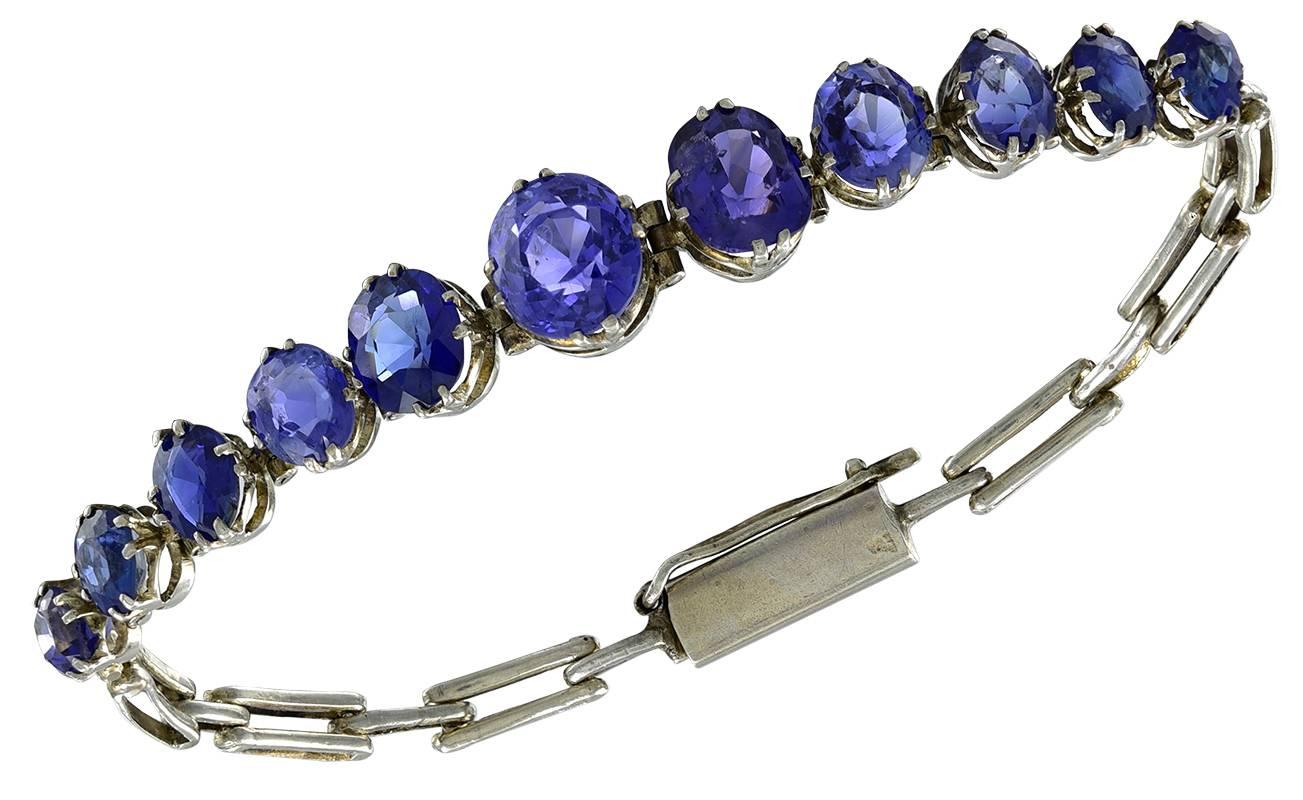 The eleven Blue Sapphires of various pleasant hues, including one that has Purple tones, are set in Silver Mounts with a Silver strap.
Total Sapphire weight approximately 8 carats.
Condition: Good
Length of Bracelet:  15.5 cm       6 1/2 