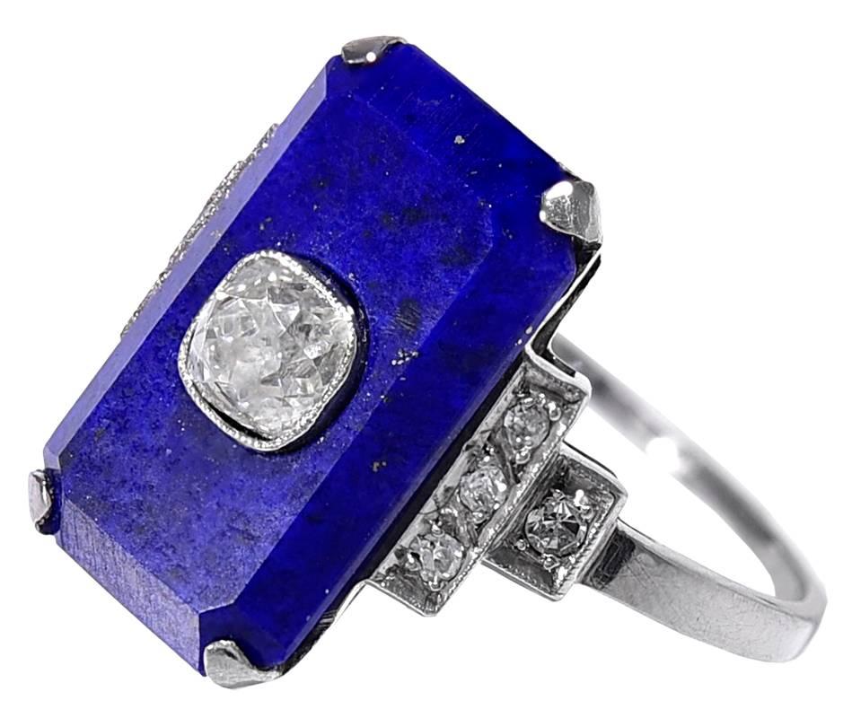 The vibrant Lapis tablet centrally set with a high crowned Old European cut Diamond of good colour and clarity weighing approximately 40 points, to Diamond set 4 stone shoulders and a plain shank with the 950 Platinum mark.
Condition: Good
Finger