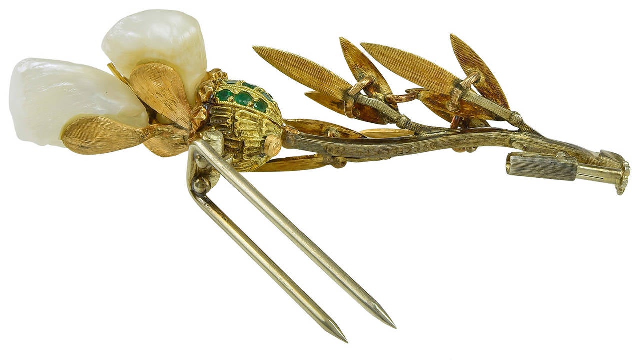 Comprising three Baroque Pearl petals with a marvellous lustre, mounted in a Flower Cup set with twenty one Green Garnets, on a leafy stem. The reverse with a double prong pin and signed on the stem Buccellati 750, for 18k Gold.
Dimensions:   2 