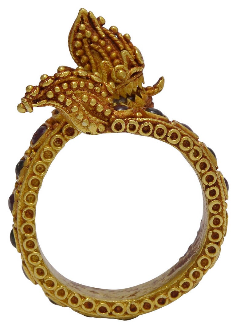 The head with protruding tongue between sharp looking teeth, the Dragons body set with alternating Rubies and Green Glass Cabochons to an intricately Gold beaded tail. The Ring is made of high Karat Gold, at least 20K or more and would have belonged