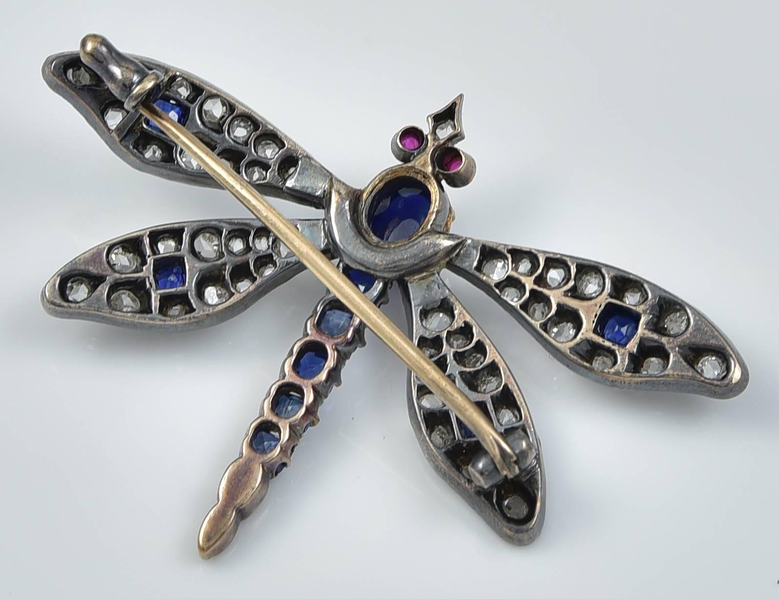 The body set with a cabochon Sapphire and five faceted Sapphires and the head with cabochon Ruby Eyes. The four wings contain over fifty Rose Diamonds and a faceted Sapphire in each and the Dragonfly is constructed of 18k Gold and Silver. The