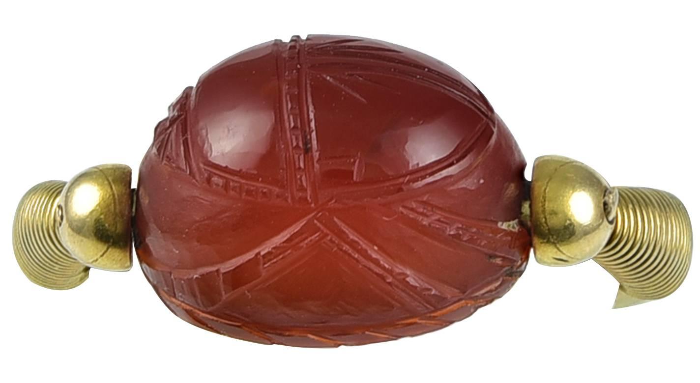 The high domed Scarab of pleasing proportions and carved from a piece of rich Carnelian, the reverse engraved with a striding figure holding a staff, all within a hatched surround. The Gold mount, which is modelled in the style of 2500 years ago, is