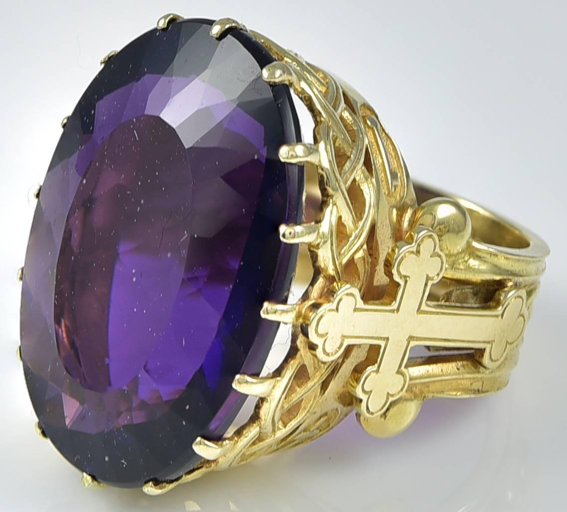 The Siberian Amethyst of astounding hue and richness, the like of which is only seen in Royal Regalia. The Gold mount with a Cross on each shoulder and in oval recesses on either side, are an anchor and a flaming heart and a key and a Latin