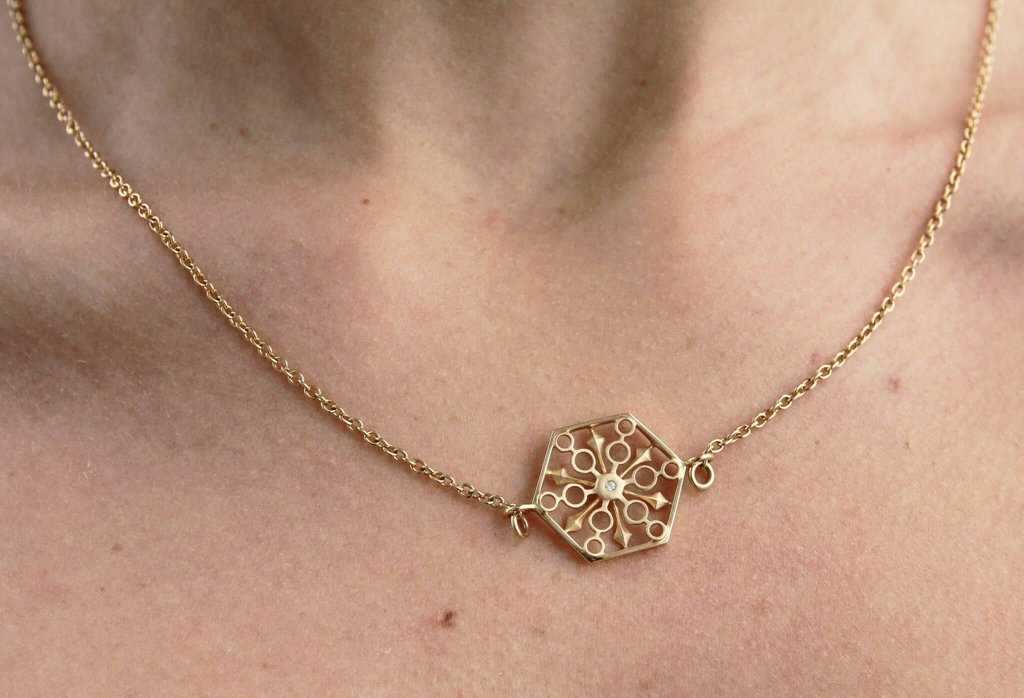 Thoscene collection snowflake necklace in 18K Yellow Gold with 1 round white diamond at 2.5mm. 

The Thoscene collection is inspired by fractals as found in ancient art and architecture, including ruins of the Indonesians, Babylonians, Egyptians,