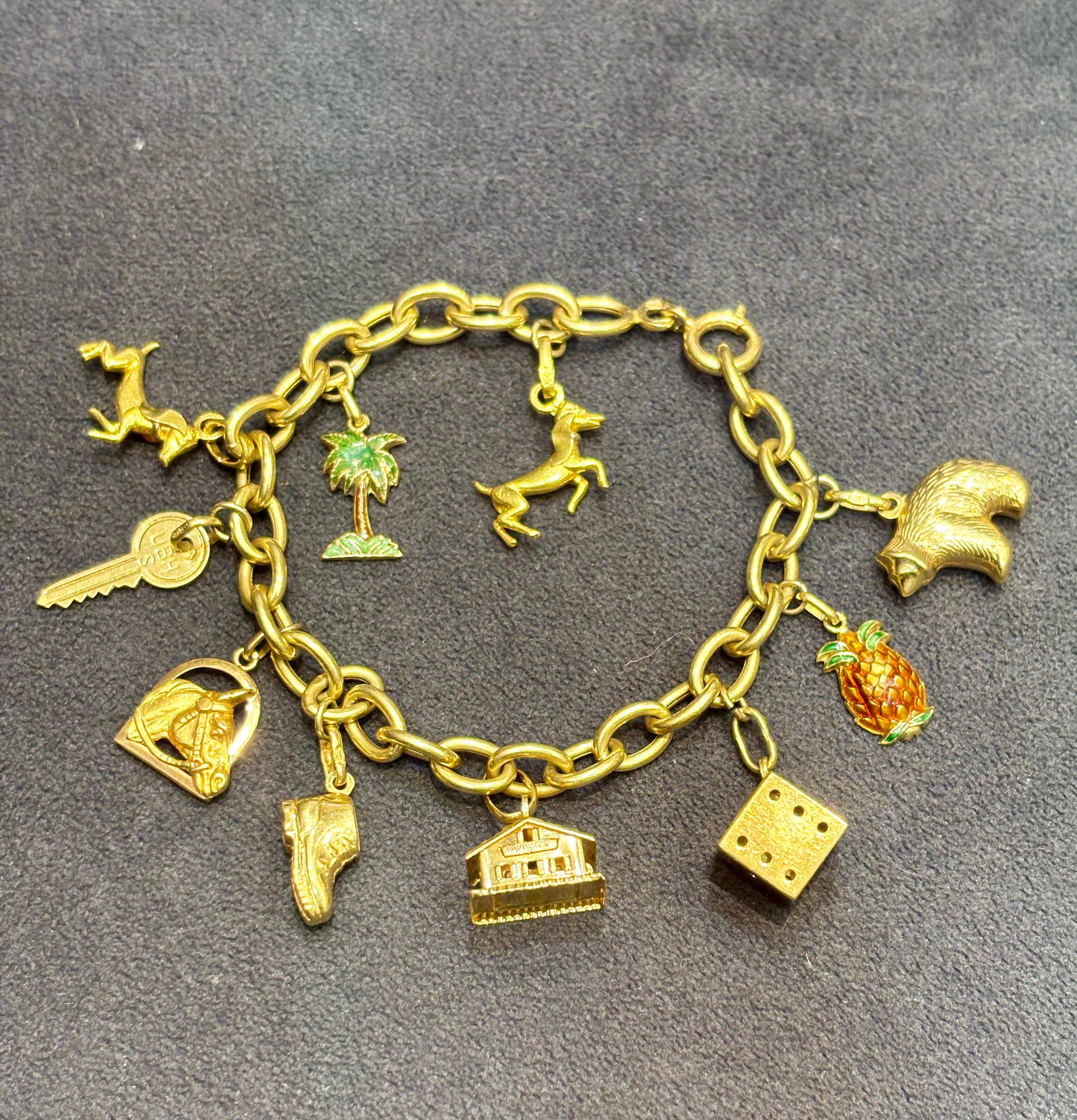 Ce bracelet à breloques en or 18 carats des années 1970 d'UnoAErre comporte 10 breloques originales estampillées en forme de maison, de dé, de botte, de palmier, d'ours, d'ananas, de tête de cheval, de clé et de 2 chiens. Il s'agit d'une belle pièce