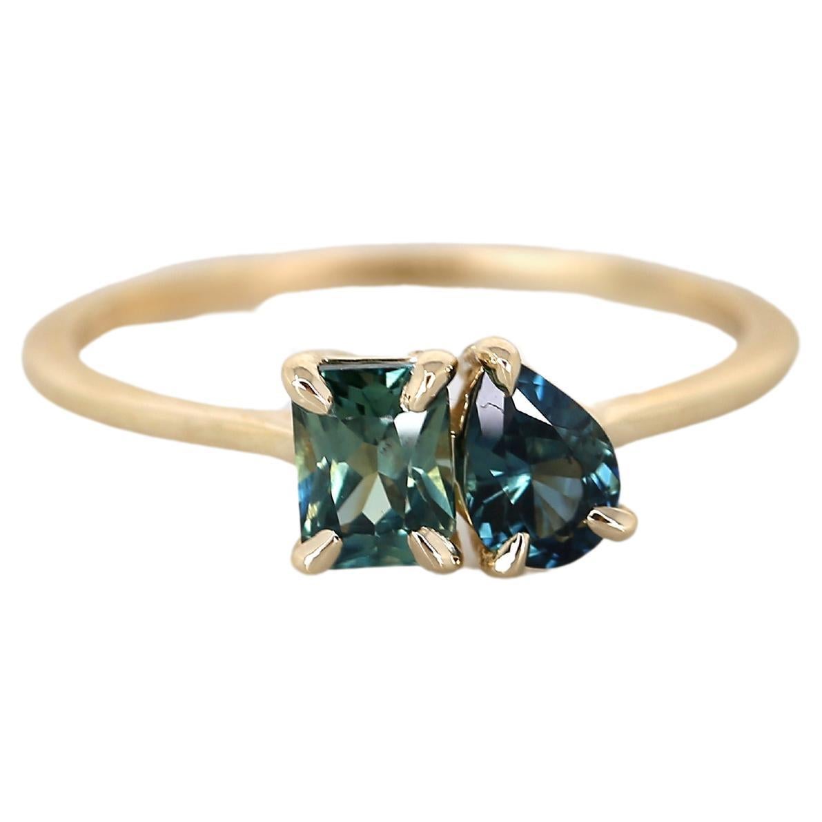Introducing our dainty Toi et Moi ring, Gemini, a stunning one-of-a-kind piece adorned with various shades of natural teal sapphires, meticulously hand-mounted by our expert artisans. This timeless masterpiece is the epitome of elegance and
