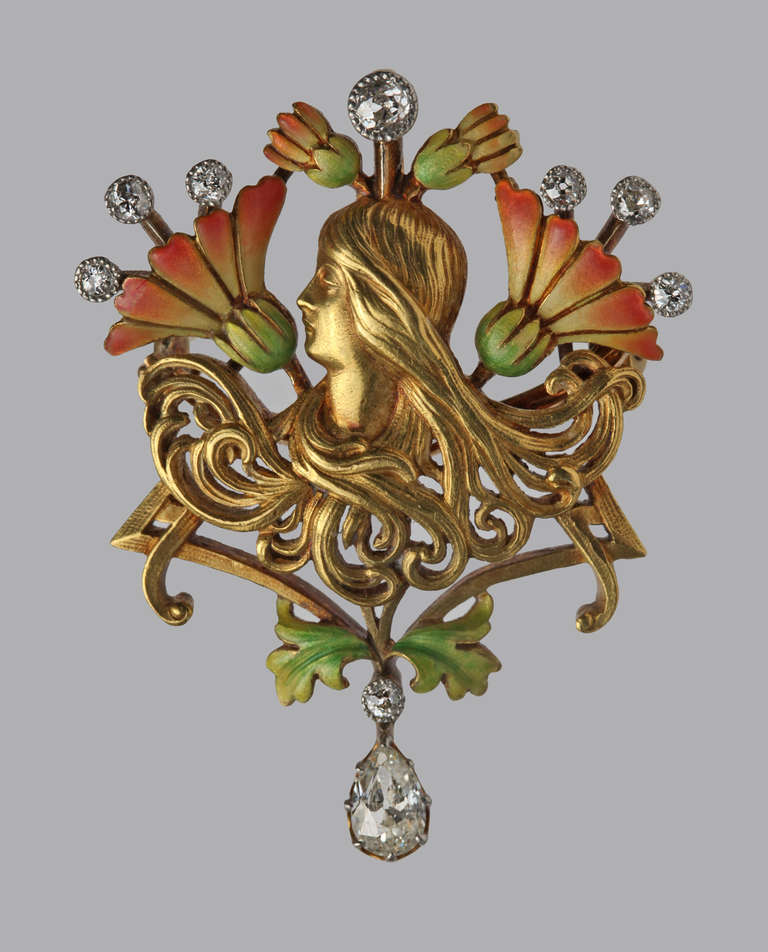 An iconic Mucha style Art Nouveau portrait in gold of a young girl with cascades of sinuous hair curls, set against a formalised arrangement of chrysanthemum flowers symbolising good fortune.
As Vivienne Becker mentions in Art Nouveau Jewelry,