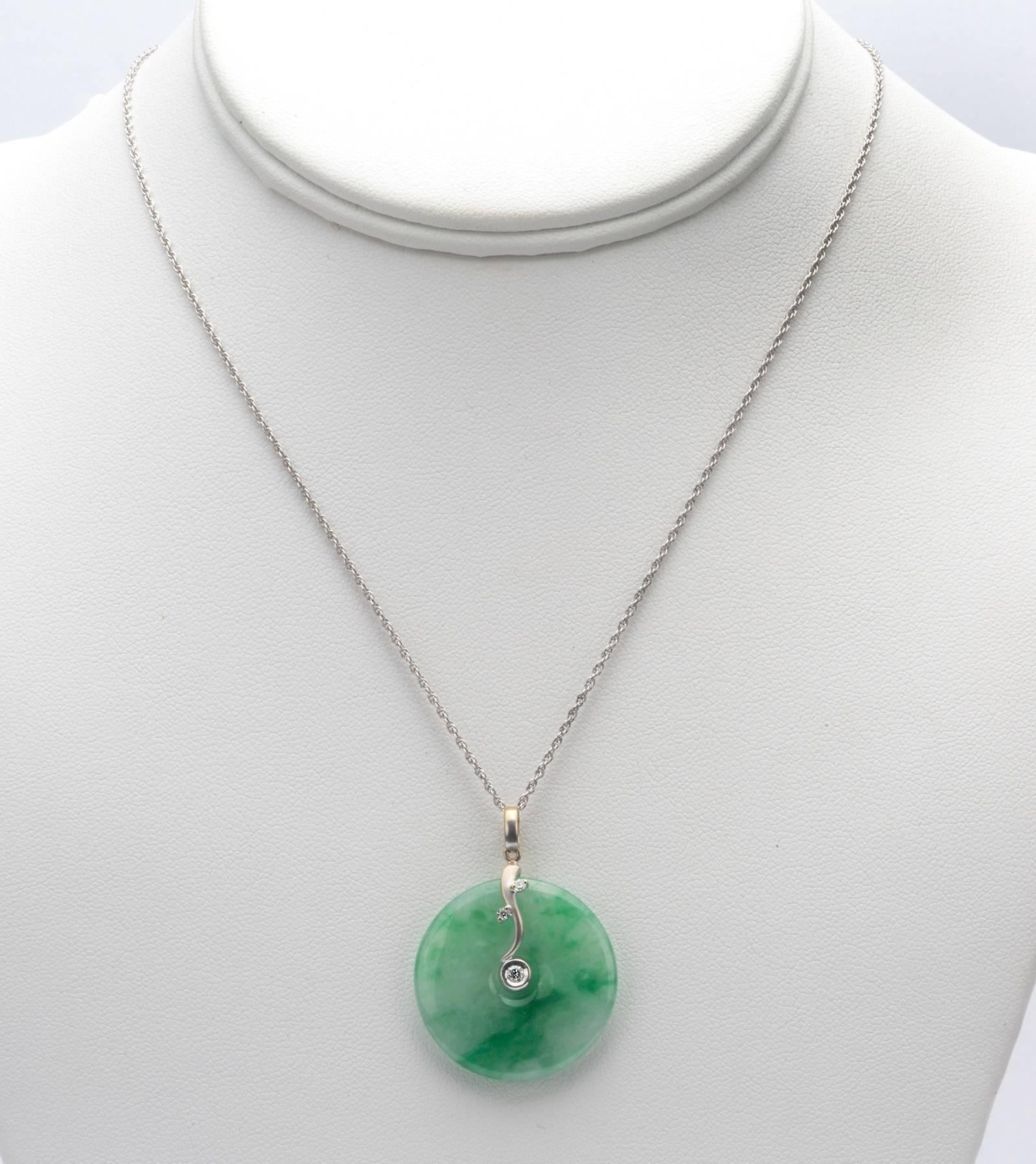 Clear green round Jade pendant with 18k white gold and three diamonds.  Hangs from a 14k yellow gold chain.  This item has been tested and verified by a GIA graduate gemologist.