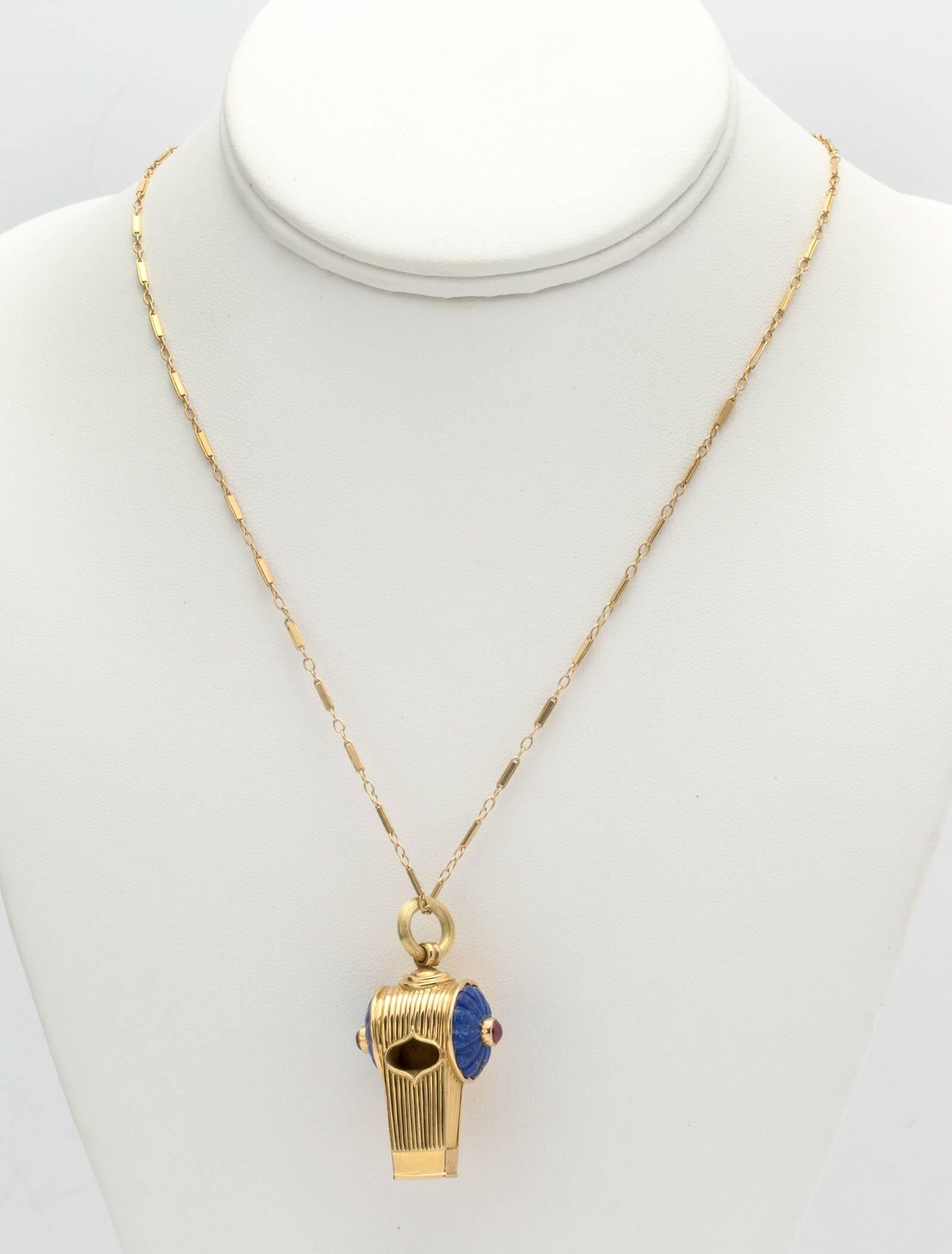 18k yellow gold whistle decorated with carved blue lapis and cabochon Ruby center.   It hangs from a 25