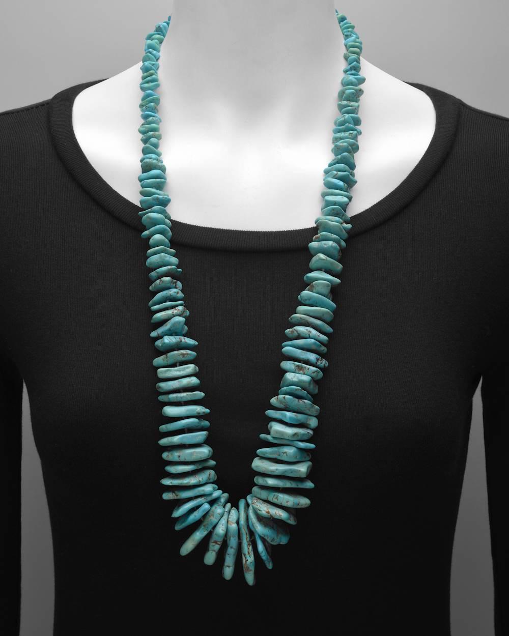 Turquoise bead long necklace, composed of graduated rough turquoise beads, strung on a silk cord, with a silver hook clasp.