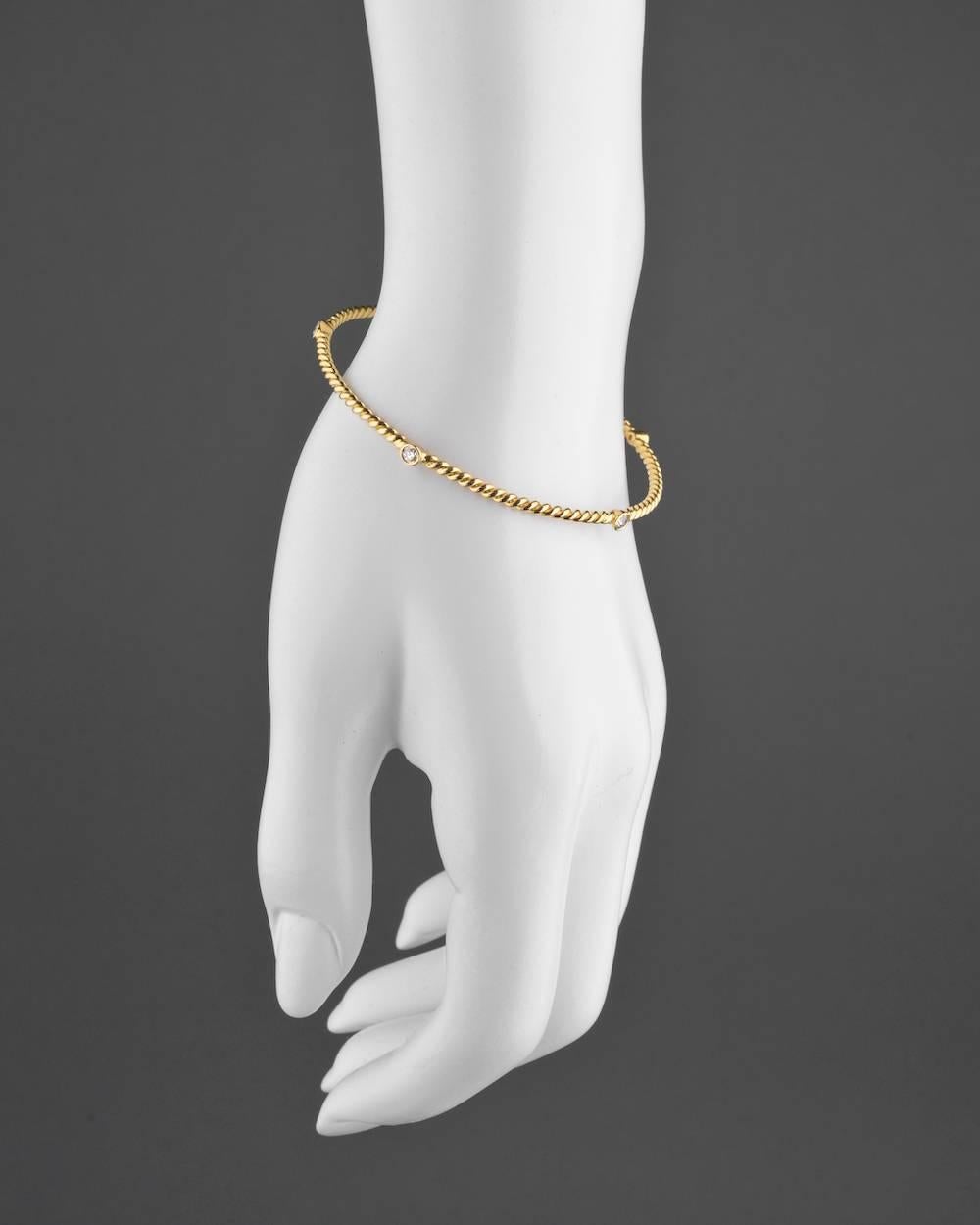Circular bangle bracelet in twistwire 18k yellow gold with round-cut diamonds. Five diamonds weighing 0.40 total carats. Slip on. 2.5
