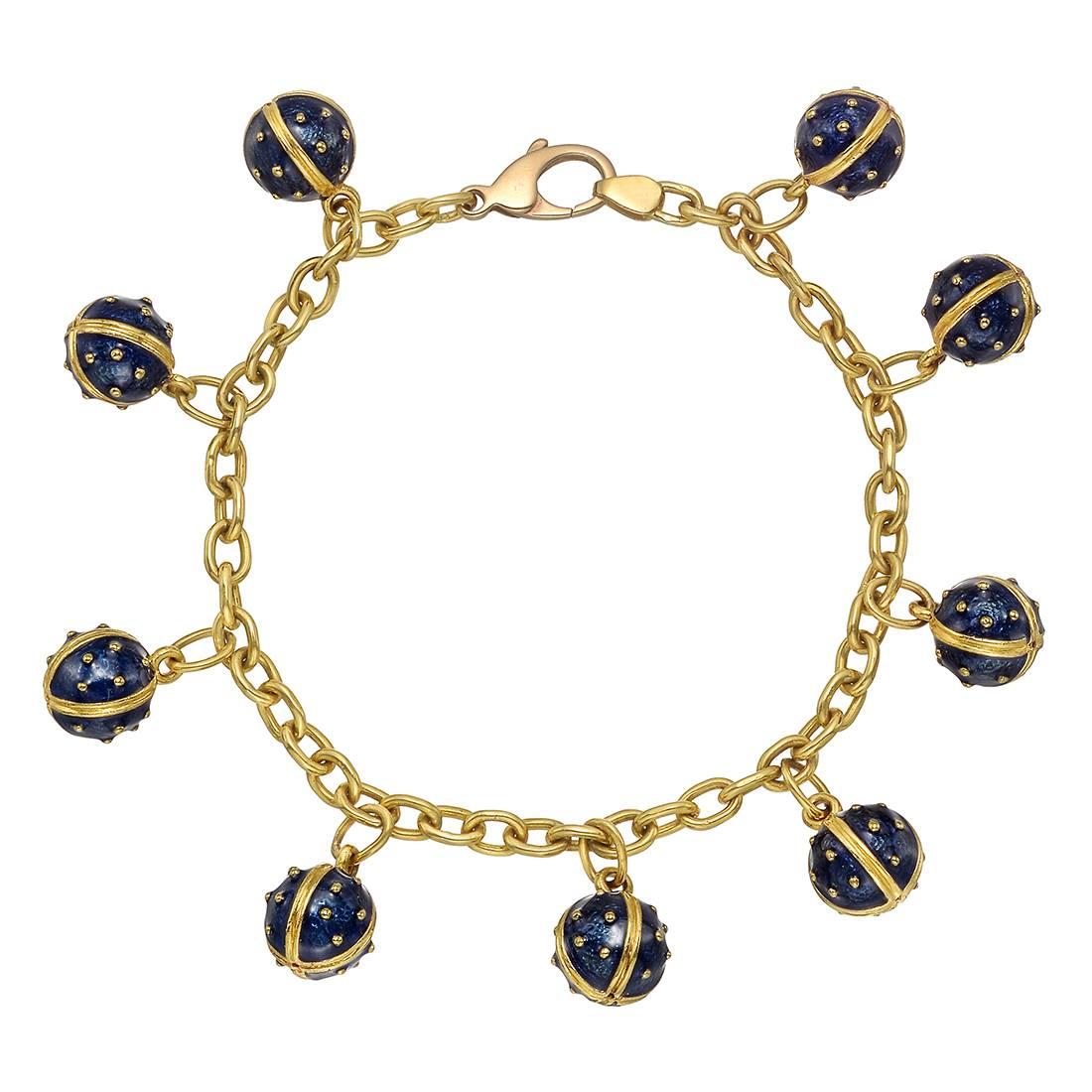 Gold charm bracelet, set with nine navy blue enamel ball charms with dots and lines, in 14k yellow gold. Each charm measuring 0.4