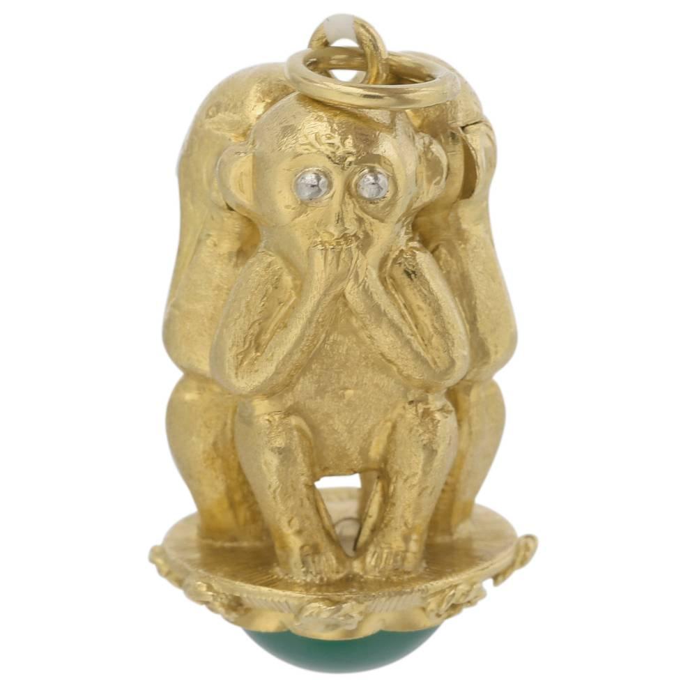 Gold charm depicting the three wise monkeys (hear no evil, speak no evil, see no evil), in 18k yellow gold, with a cabochon dyed green chalcedony at base. 1
