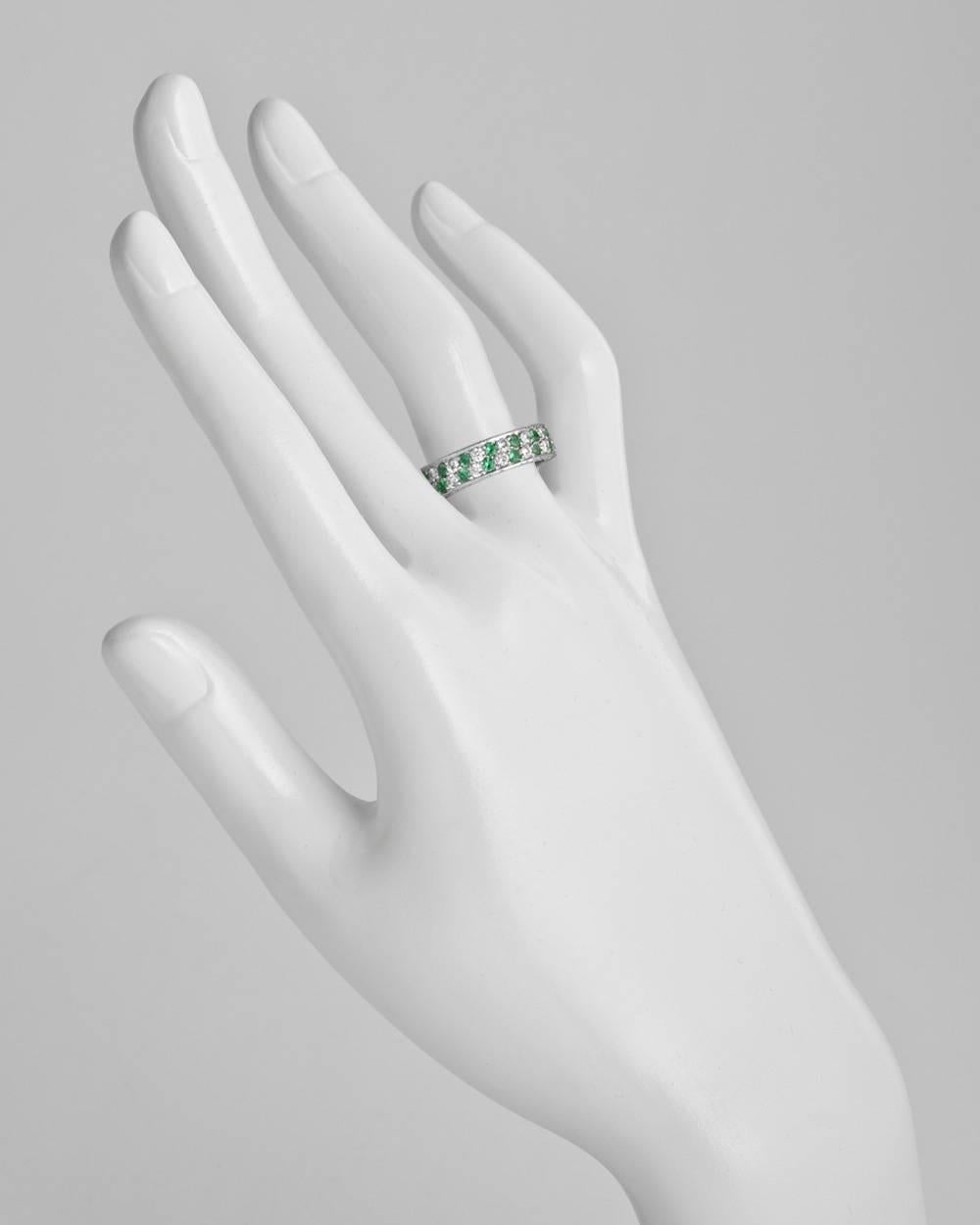 Diamond and emerald partial band ring composed of two rows of alternating pavé-set diamonds and emeralds in a slight diagonal pattern, with pavé set diamond top and bottom profiles, in platinum. Diamonds weighing approximately 1.25 total carats.