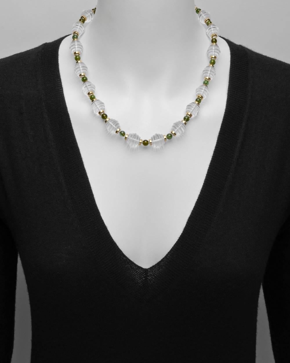 Bead necklace, composed of larger beehive-shaped rock crystal beads with 14k yellow gold alternating with smaller round-shaped green tourmaline beads, signed Trianon. Screw-style clasp at back. 20.5