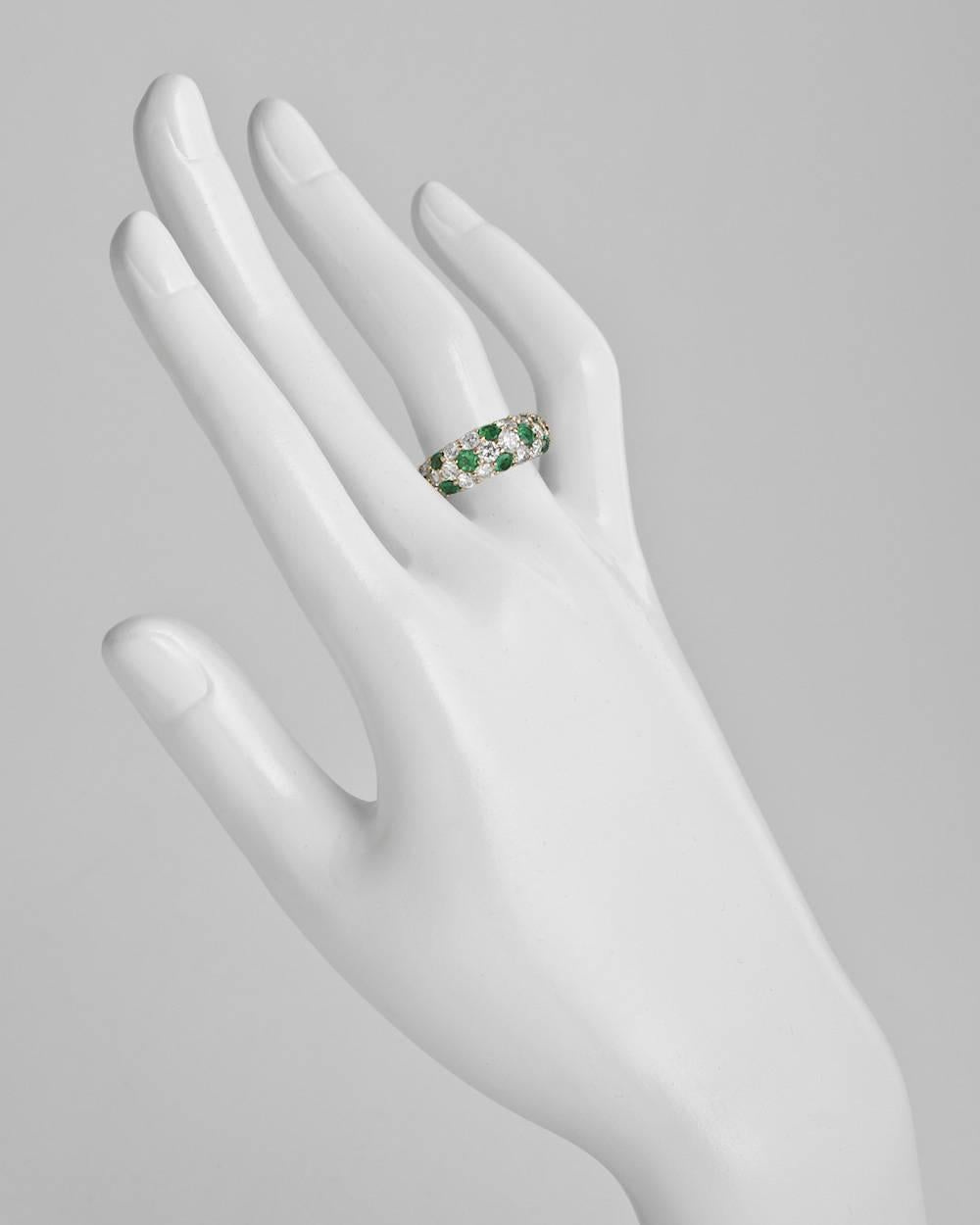 Wide domed band ring, partway-set with round emeralds and round brilliant-cut diamonds, mounted in 18k yellow gold. Emeralds weighing approximately 0.96 total carats and diamonds weighing approximately 1.64 total carats. 4.5mm band width. Size 7.