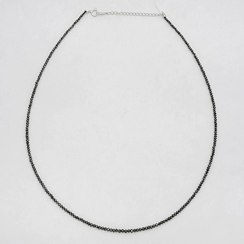 Black diamond chain necklace, showcasing faceted black diamond beads weighing approximately 22.56 total carats, secured by an 18k white gold chain clasp at back. Beads graduated from approximately 1.75mm at the clasp to approximately 3.0mm at the