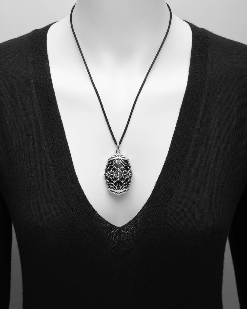 Large oval-shaped black onyx pendant, with polished scroll work cage motif in 18k white gold accented by round-cut diamonds, on a 24" black silk cord. Diamonds altogether weighing approximately 1.20 total carats. Designed by Ivanka Trump.