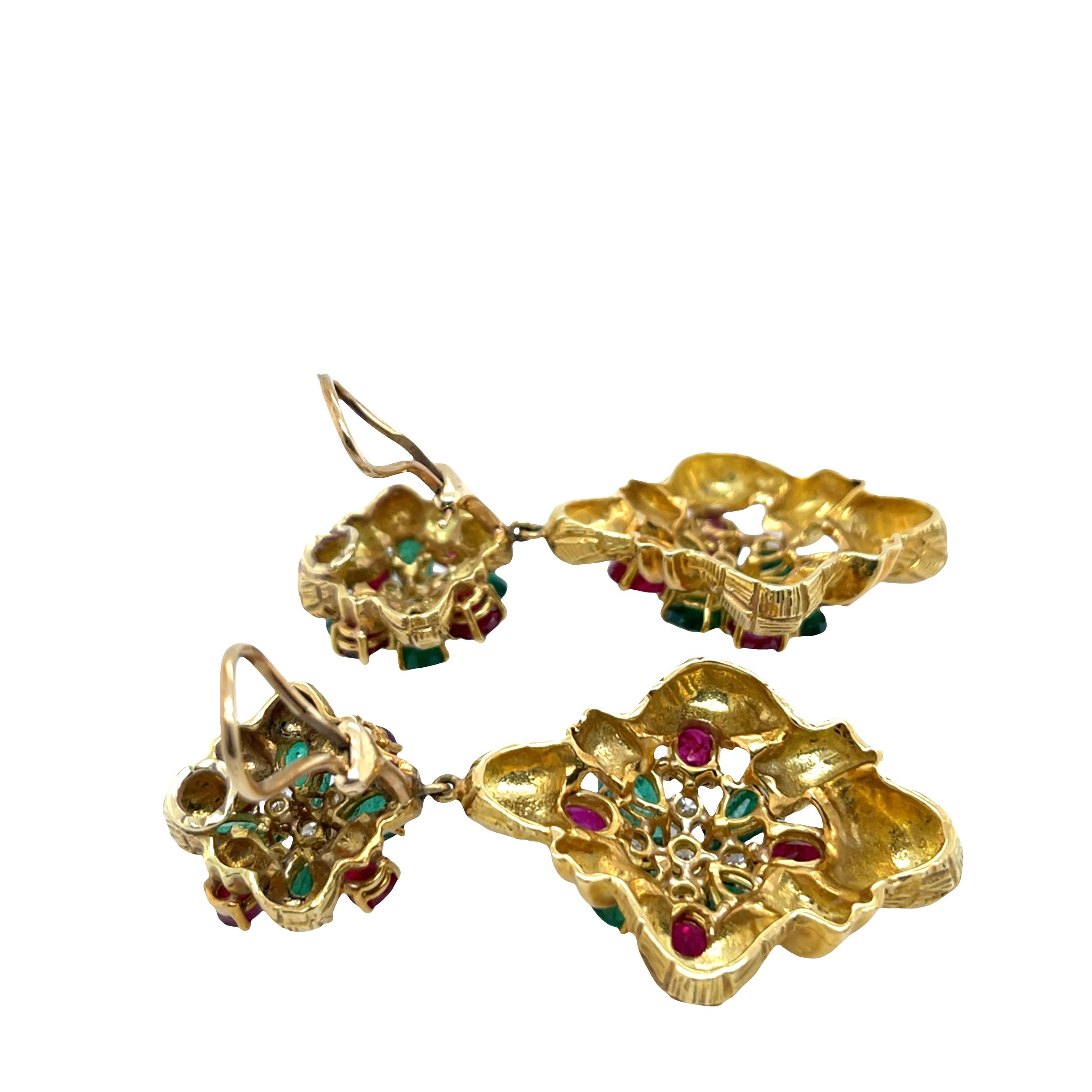 Questi eleganti orecchini vintage presentano una vibrante combinazione di rubini e smeraldi naturali, accentuati da diamanti scintillanti, il tutto incastonato in un ricco oro giallo 18 ct. Il design classico ma colorato offre un tocco di