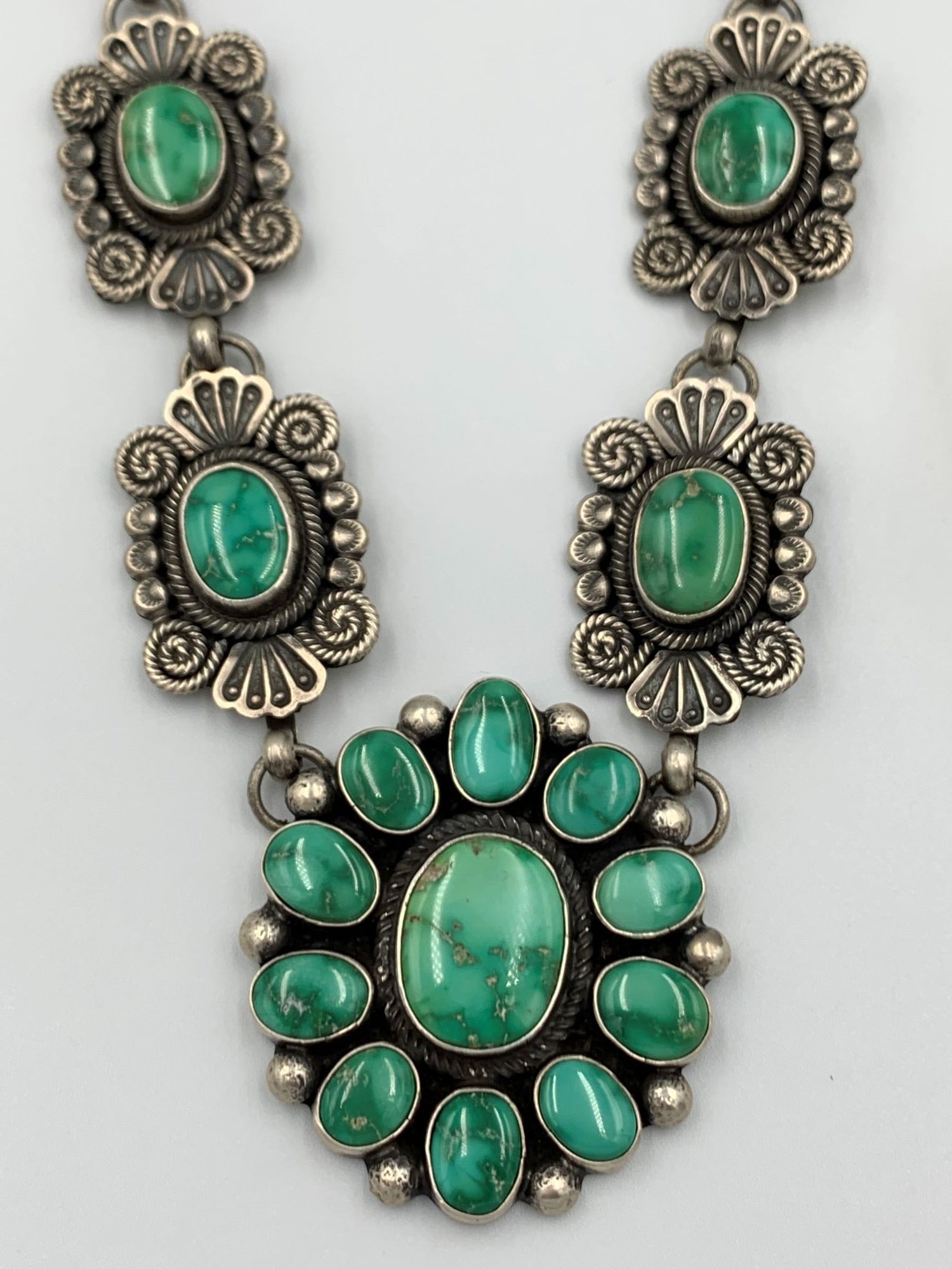 Sterling silver necklace by Navajo silversmith Leon Martinez. The adjustable 30-35” necklace featuring fine stamp and applique work is set with high grade Royston Turquoise.   Each of the twelve 7/8” x 1 1/4” hand stamped stations display a 3/8” x