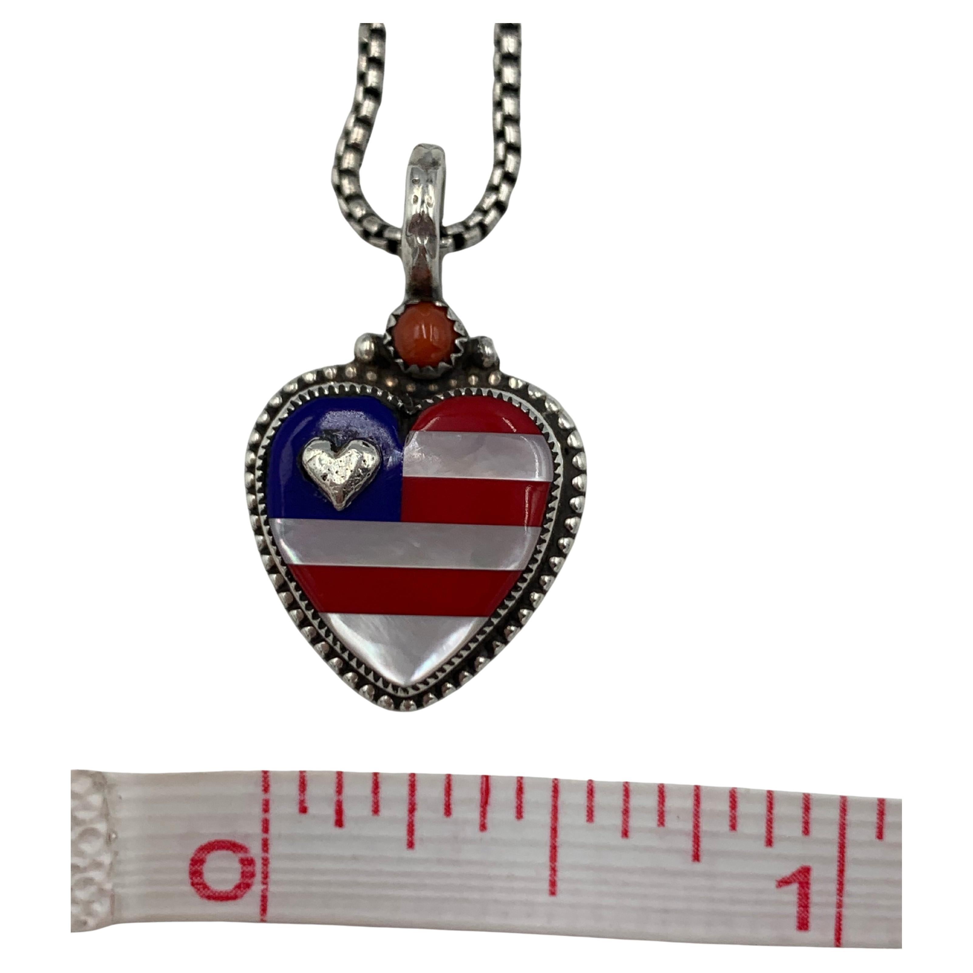 Sterling Silver Flag pendant created with beautiful inlayed heart showing the USA flag design and colors.  The pendant is on a 20: sterling sliver chain with a lobster clasp.

The heart is inlayed with semi-precious Mother-of- pearl, Blue Lapis and