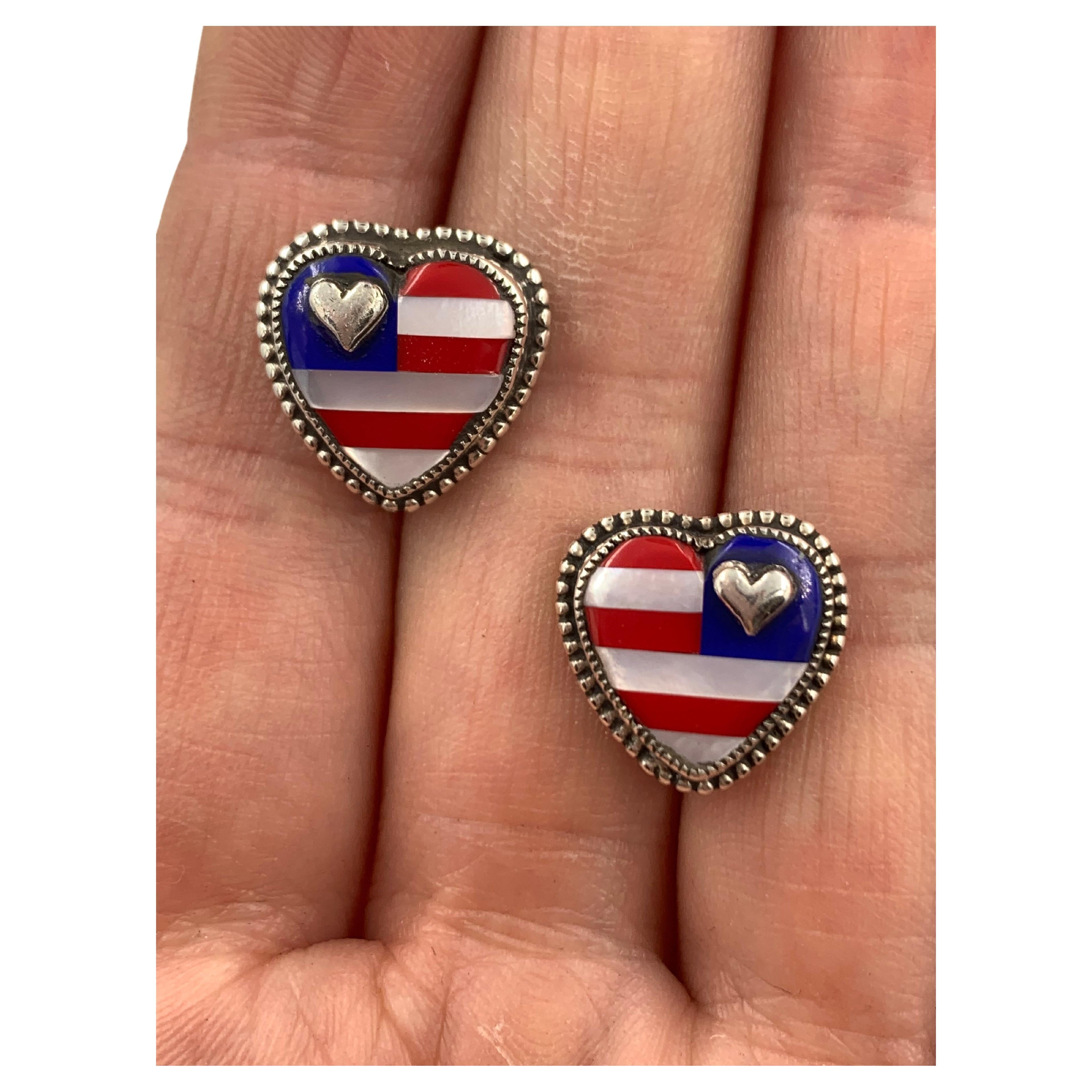 Mother-of-pearl, Blue lapis, and red coral inlay create a flag motif. Sterling silver hearts highlight the patriotic feel of these earrings.

Measures: Heart are 3/8″ x 3/8″ with standard post backs

Creators:
Nestled in the mountains of Durango,