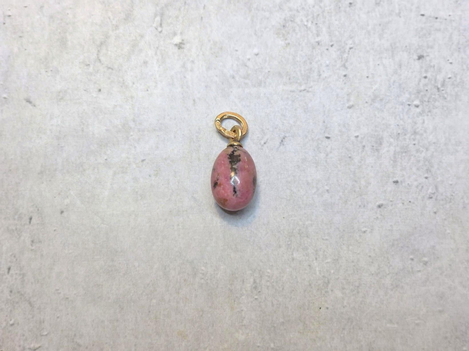 Nous avons le plaisir de vous présenter une autre pièce exceptionnelle de notre collection - un magnifique et très inhabituel pendentif miniature en forme d'œuf en or rose, fabriqué à partir de rhodonite véritable. Cette pièce exquise est attribuée