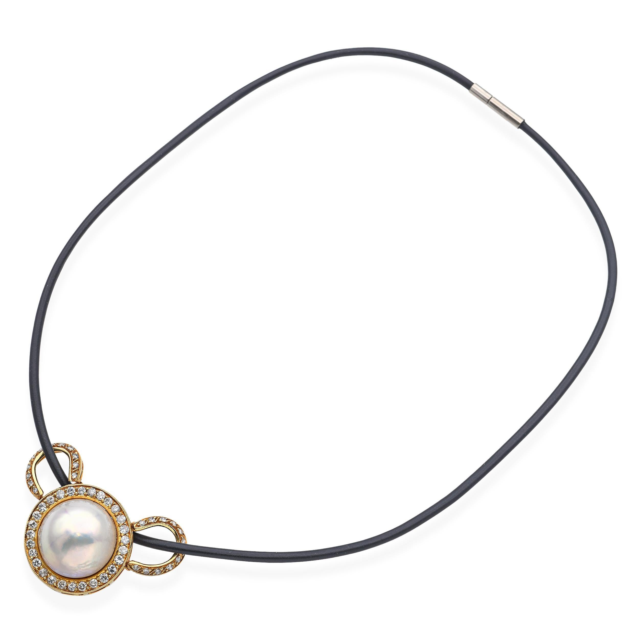 Questa collana tenuta in eredità mette in mostra una luminosa perla Mabe incastonata in un ricco oro giallo 18 carati, circondata da circa 1,08 carati di peso totale di diamanti a taglio brillante. Il ciondolo è sospeso a un cordone di pelle nera
