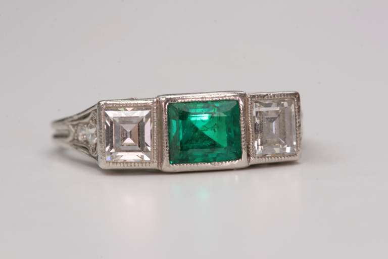 1.00cttw Step cut diamonds with 0.65ct Emerald set in a vintage platinum mounting. Circa 1920