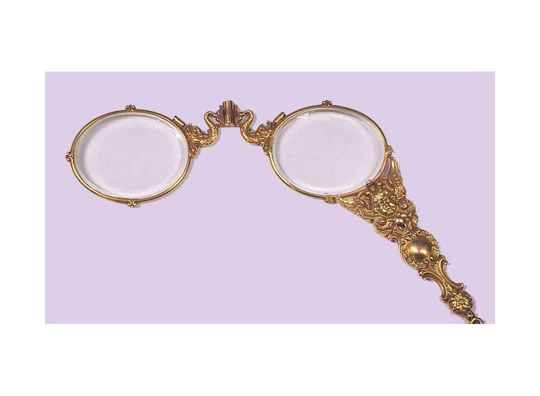 Art Nouveau 14K Gold (tested) Lorgnette, C.1900. The Lorgnette depicting a winged cherub amidst scroll and foliage decoration, the top of lenses surmounted with a scaled fish.....could be a play on….`en lorgnette'..., push button release mechanism,