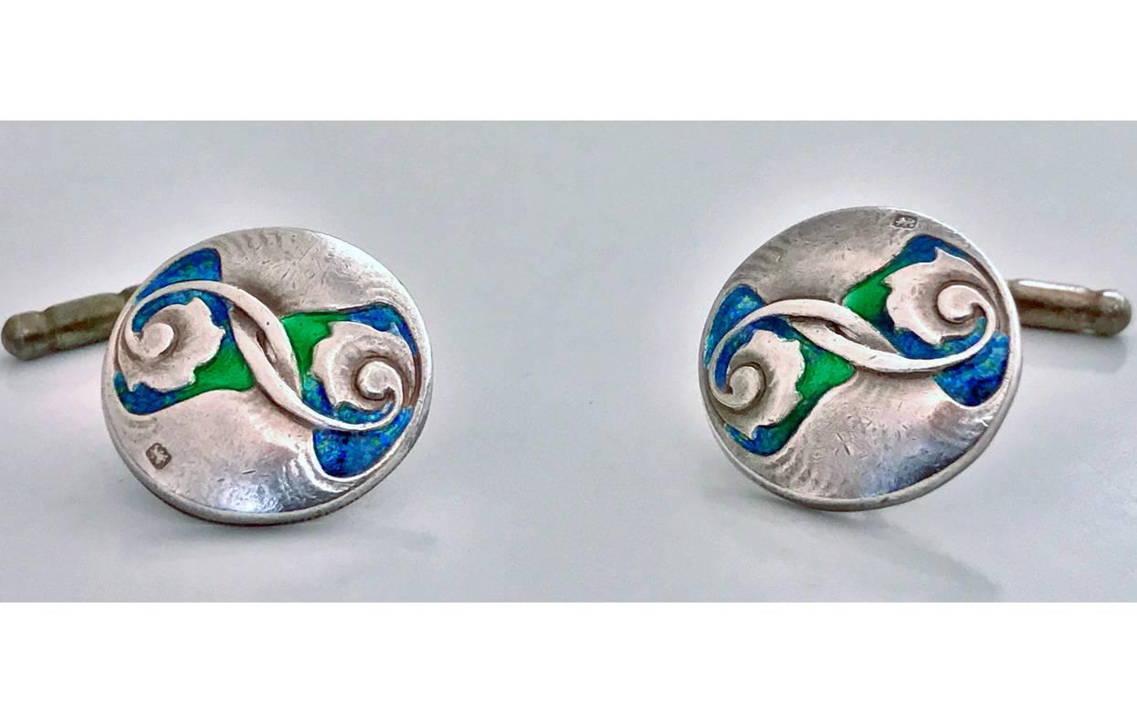 Pair Liberty & Co Archibald Knox designed Enamel Cufflinks, Birmingham 1907. The circular slightly concave cufflinks with stylised foliate and green, blue, turquoise enamel. Chain figure of eight link and groove cylinder fitments. Full Liberty