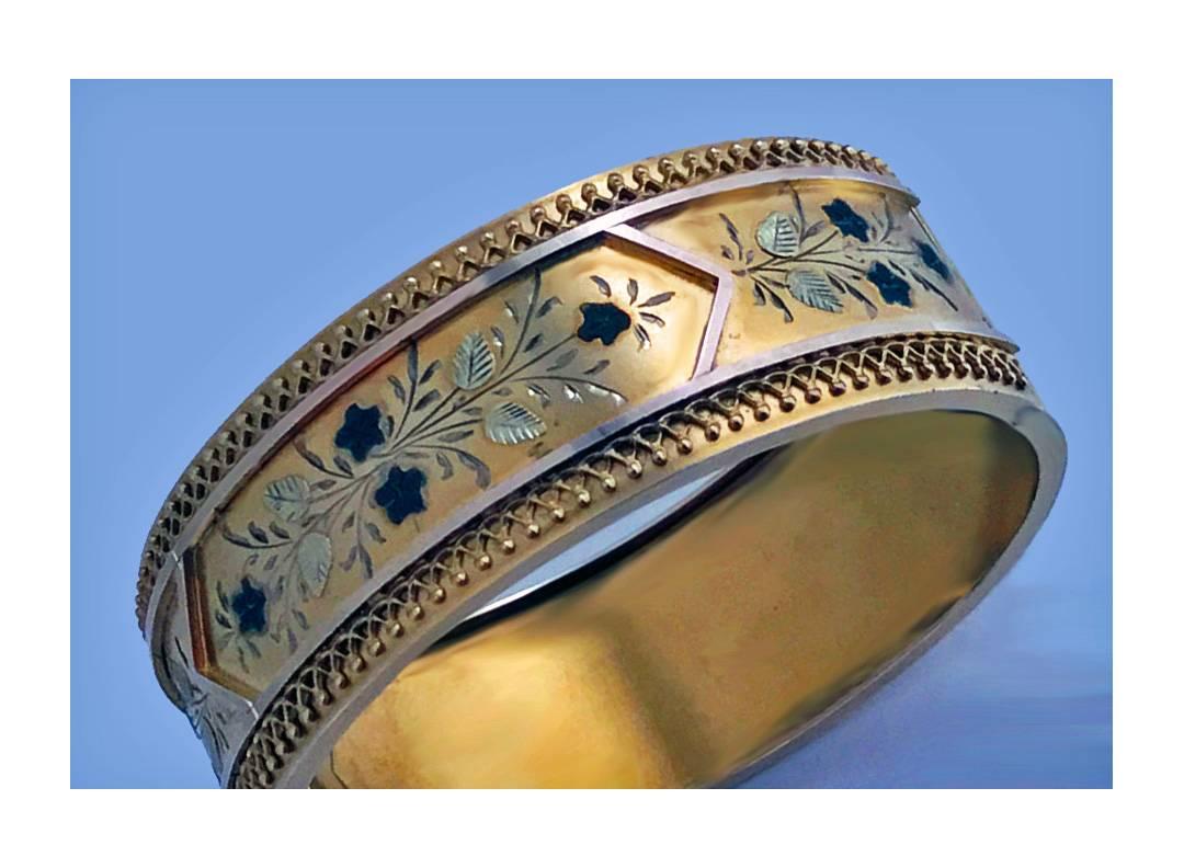 Fine Gold Etruscan Aesthetic Japonaiserie Bangle, C.1875. This mint condition Bangle of oval shape with a hinged opening, the front decorated in three colour gold with foliate motif within borders of fine etruscan work, the reverse with a hidden,