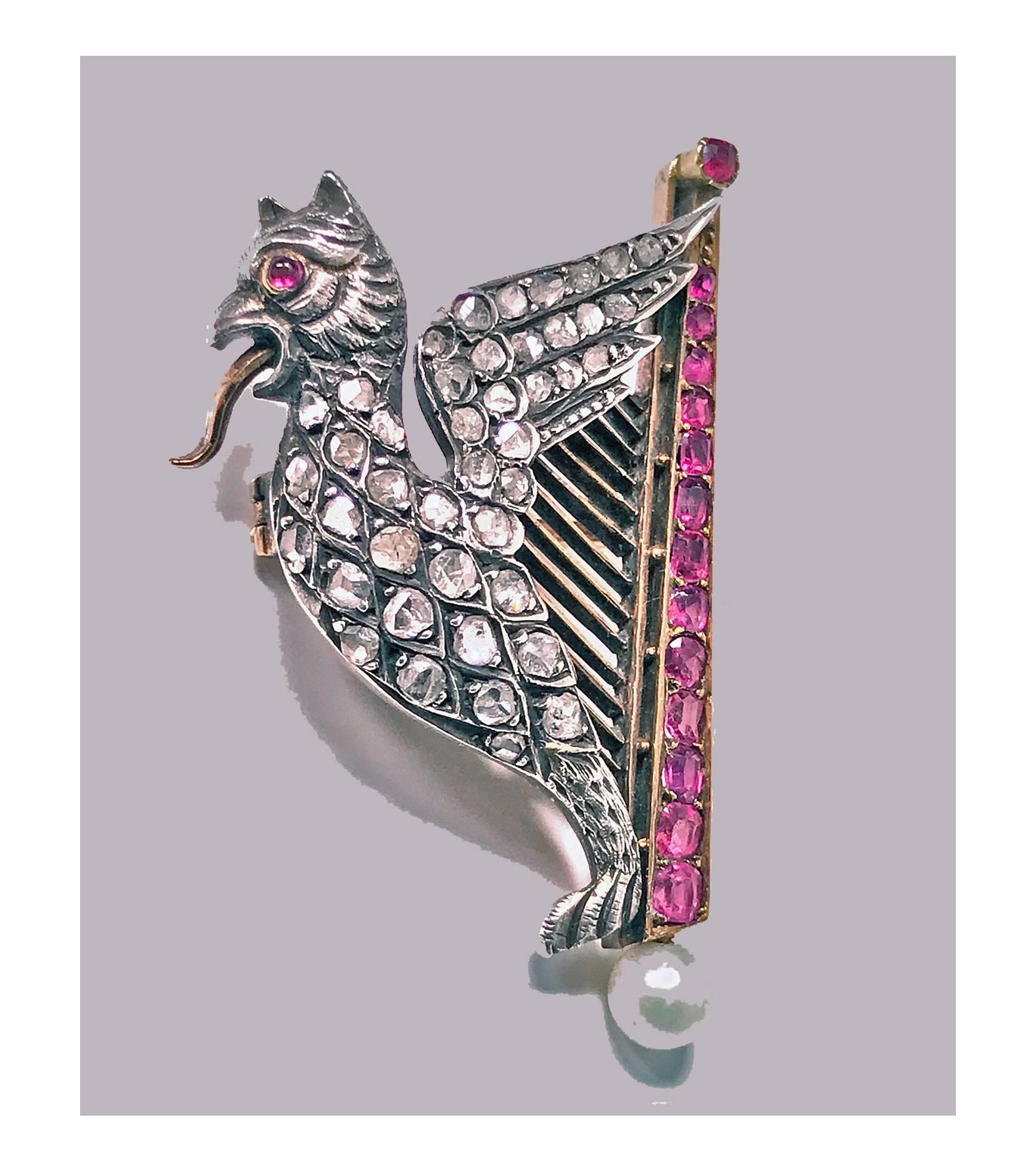 Mythical 19th Century Griffin and Lyre Ruby, Diamond, Pearl Gold Brooch, French C.1890. The winged griffin and harp brooch set in silver and 18K Gold (tested). The tongue protruding griffin set with 43 small rose cut diamonds and cabochon ruby eye,