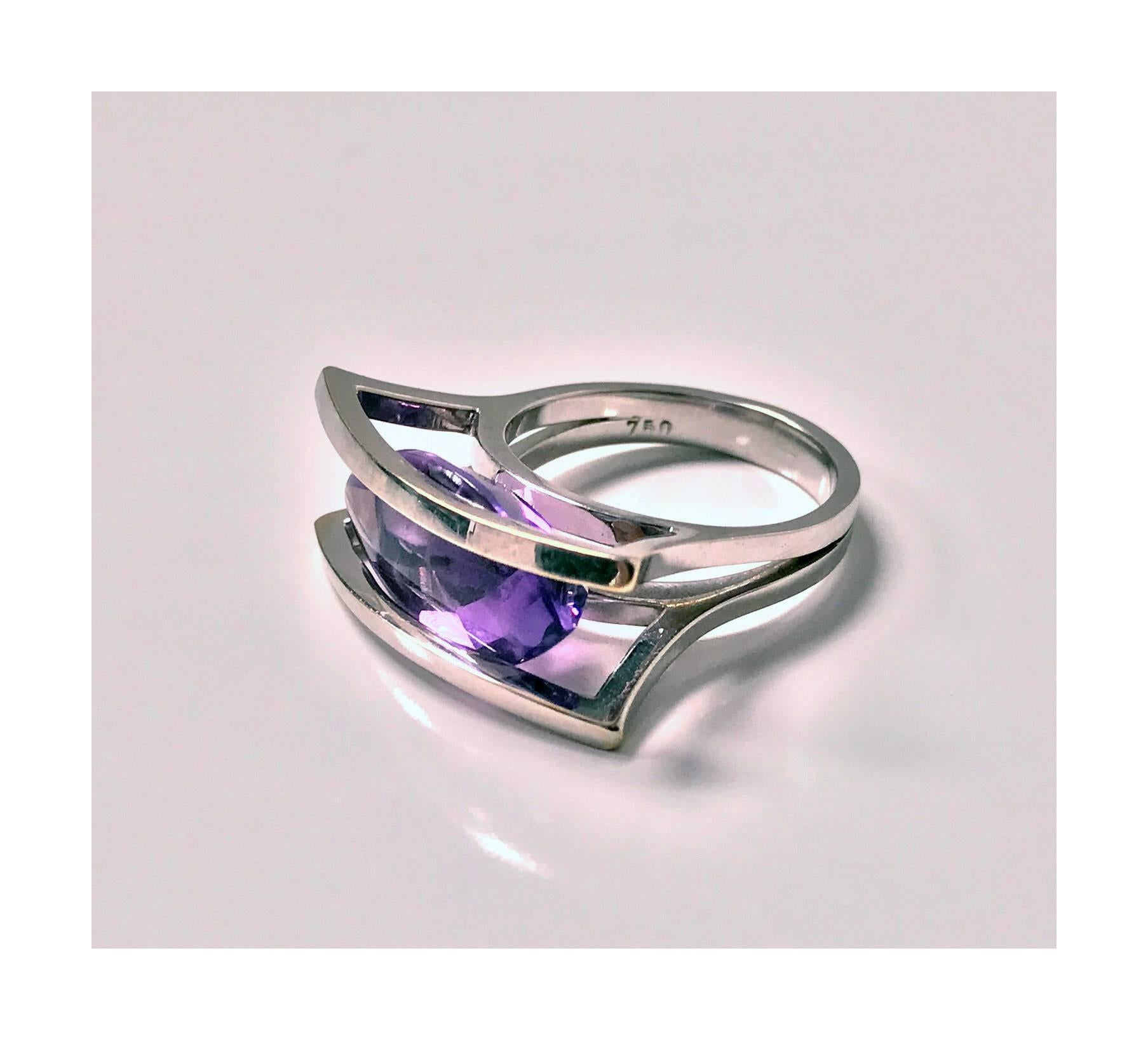 18K white gold and Amethyst modernist abstract Ring, 20th century. The ring mount of a double edge horizontal hemi spherical open design set in the centre with a purple navette shape purple amethyst. The amethyst gauging approximately 18.0 x 10.0 x